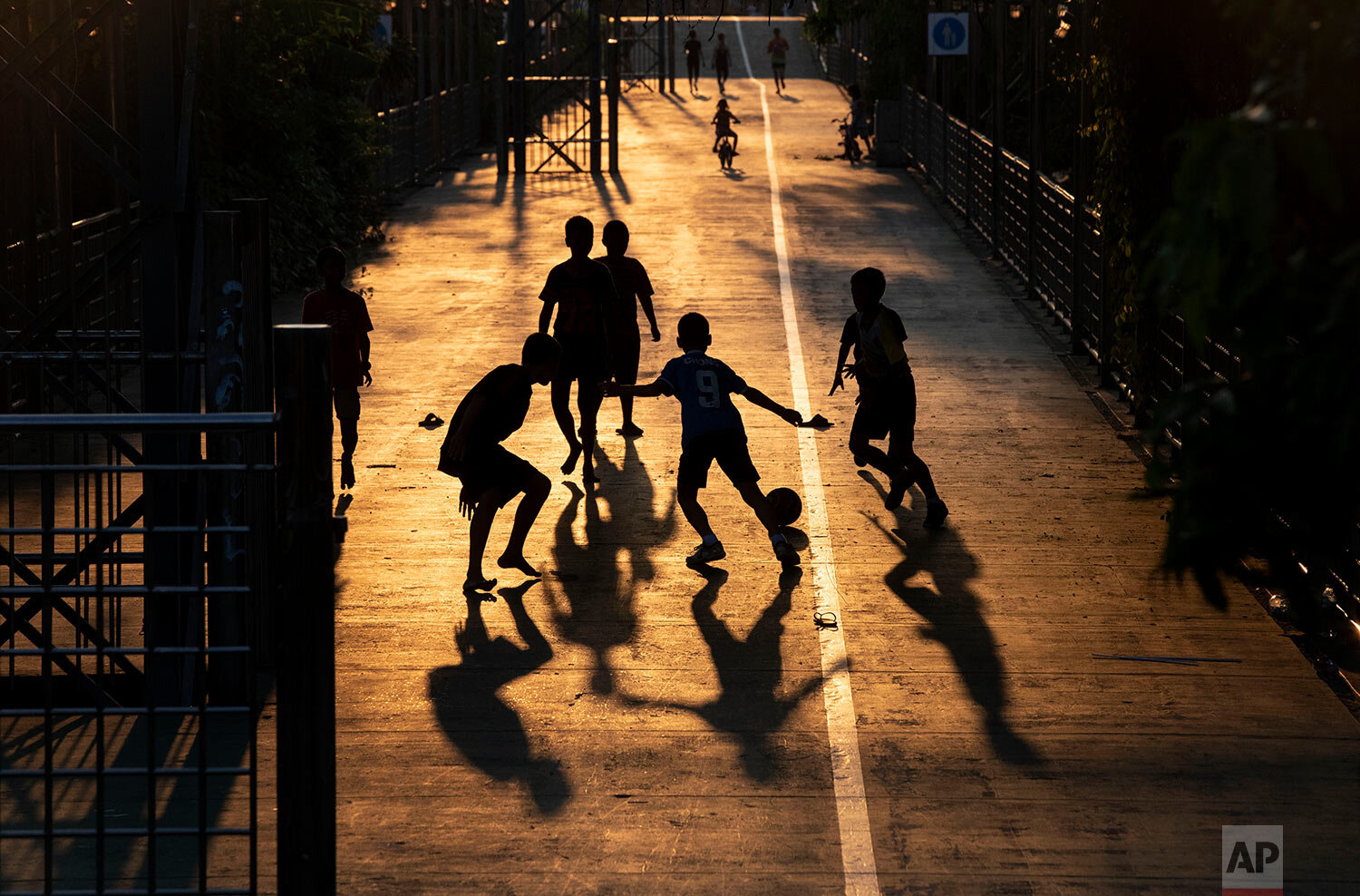  Children play soccer in the afternoon light in Bangkok, Thailand, Wednesday, March 25, 2020. (AP Photo/Gemunu Amarasinghe) 