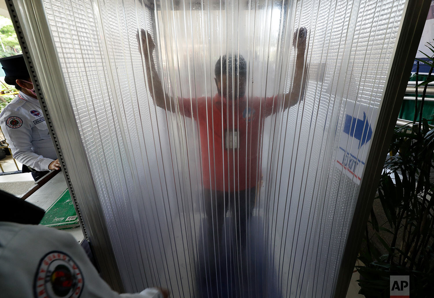  A man is disinfected inside a cubicle before entering local the city hall to prevent the spread of the new coronavirus in Manila, Philippines on Tuesday, March 24, 2020. (AP Photo/Aaron Favila) 