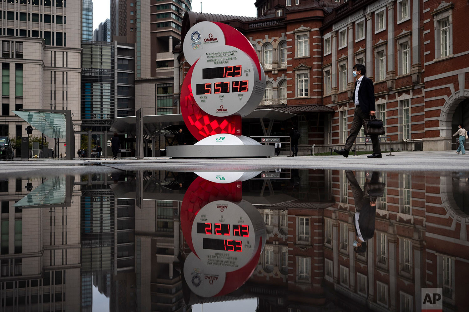 A countdown clock for the Tokyo 2020 Olympics is reflected in a puddle of water outside Tokyo Station in Tokyo, Monday, March 23, 2020. (AP Photo/Jae C. Hong) 