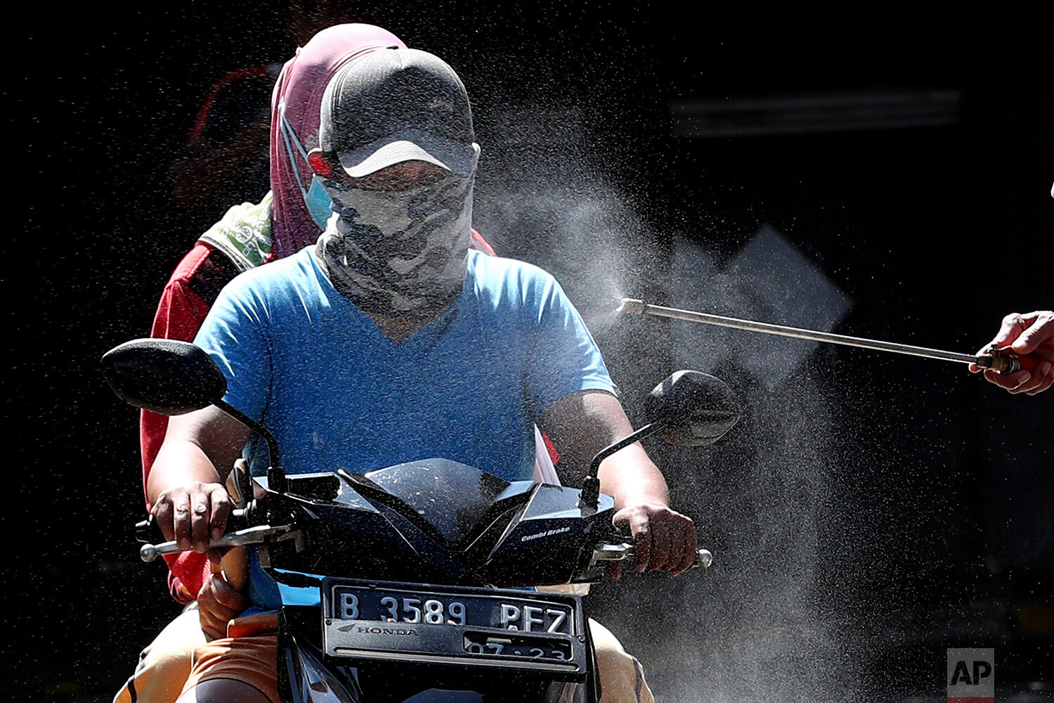  Motorists are sprayed with disinfectant in an attempt to curb the spread of the coronavirus at the gate of a housing complex in South Tangerang, Indonesia, Tuesday, March 31, 2020. (AP Photo/Tatan Syuflana) 