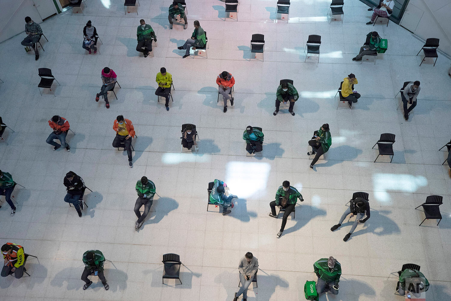  People practice social distancing in the hopes of preventing the spread of the coronavirus as they sit on chairs spread apart in a waiting area for take-away food orders at a shopping mall  in Bangkok, Thailand, Tuesday, March 24, 2020. (AP Photo/Sa