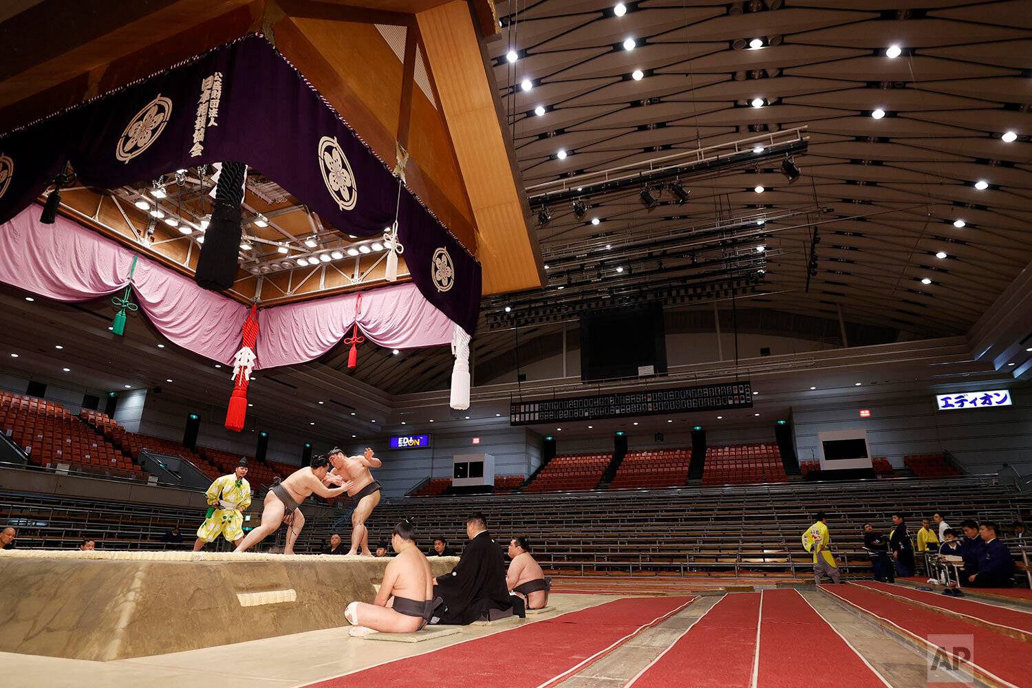  Sumo wrestlers fight on the ring as spectators' seats are empty during the Spring Grand Sumo Tournament in Osaka, western Japan, Sunday, March 8, 2020. (Kyodo News via AP) 