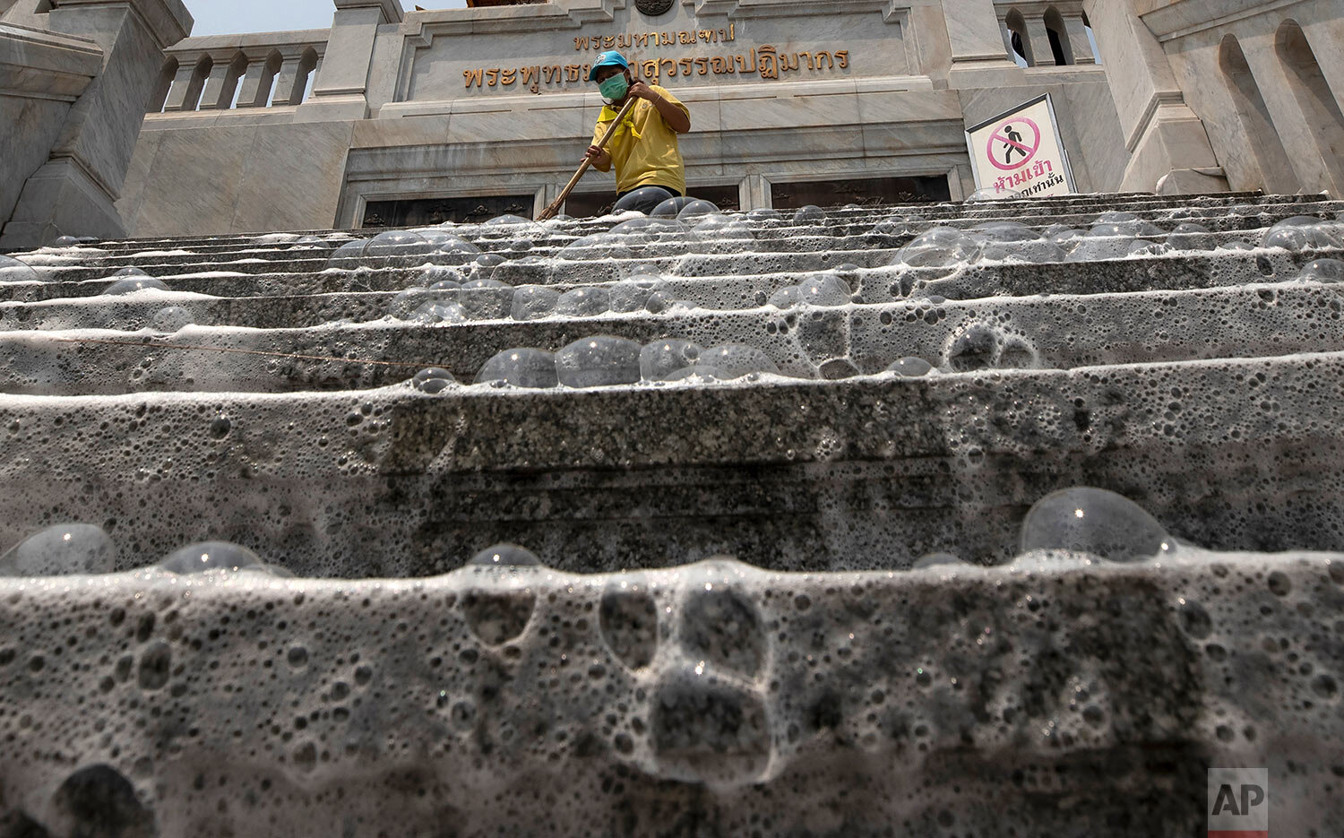  Soap bubbles cover the steps of Wat Taimit Temple as volunteers clean the public areas as a safety precaution against the new coronavirus Wednesday, March 18, 2020, in Bangkok, Thailand. (AP Photo/Sakchai Lalit) 