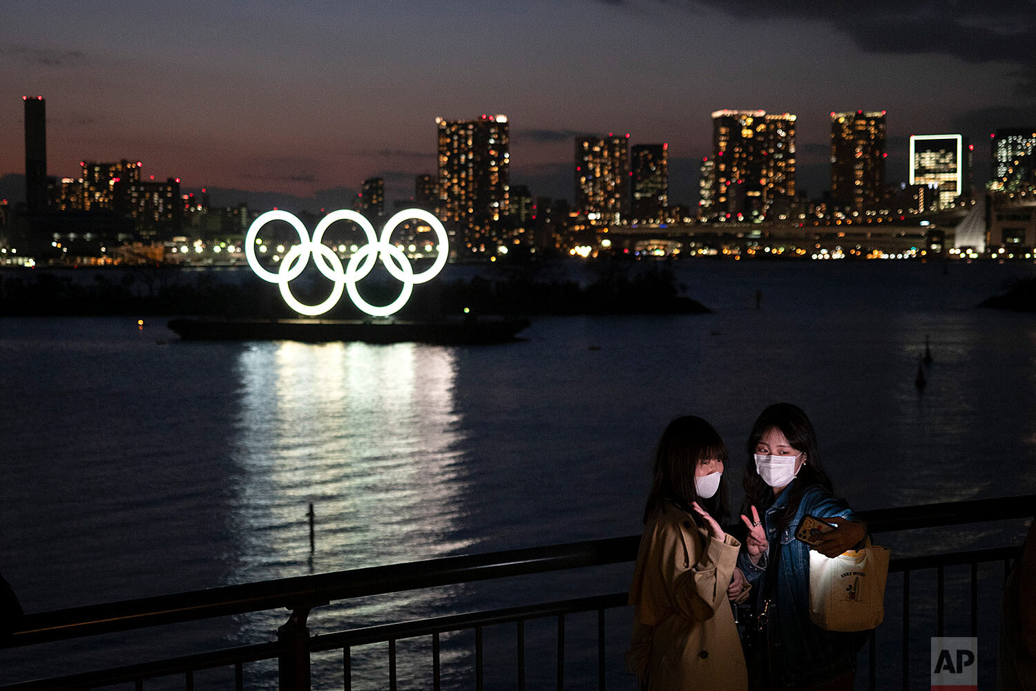  Two women take a selfie with the Olympic rings in the background in the Odaiba section of Tokyo, Thursday, March 12, 2020. (AP Photo/Jae C. Hong) 