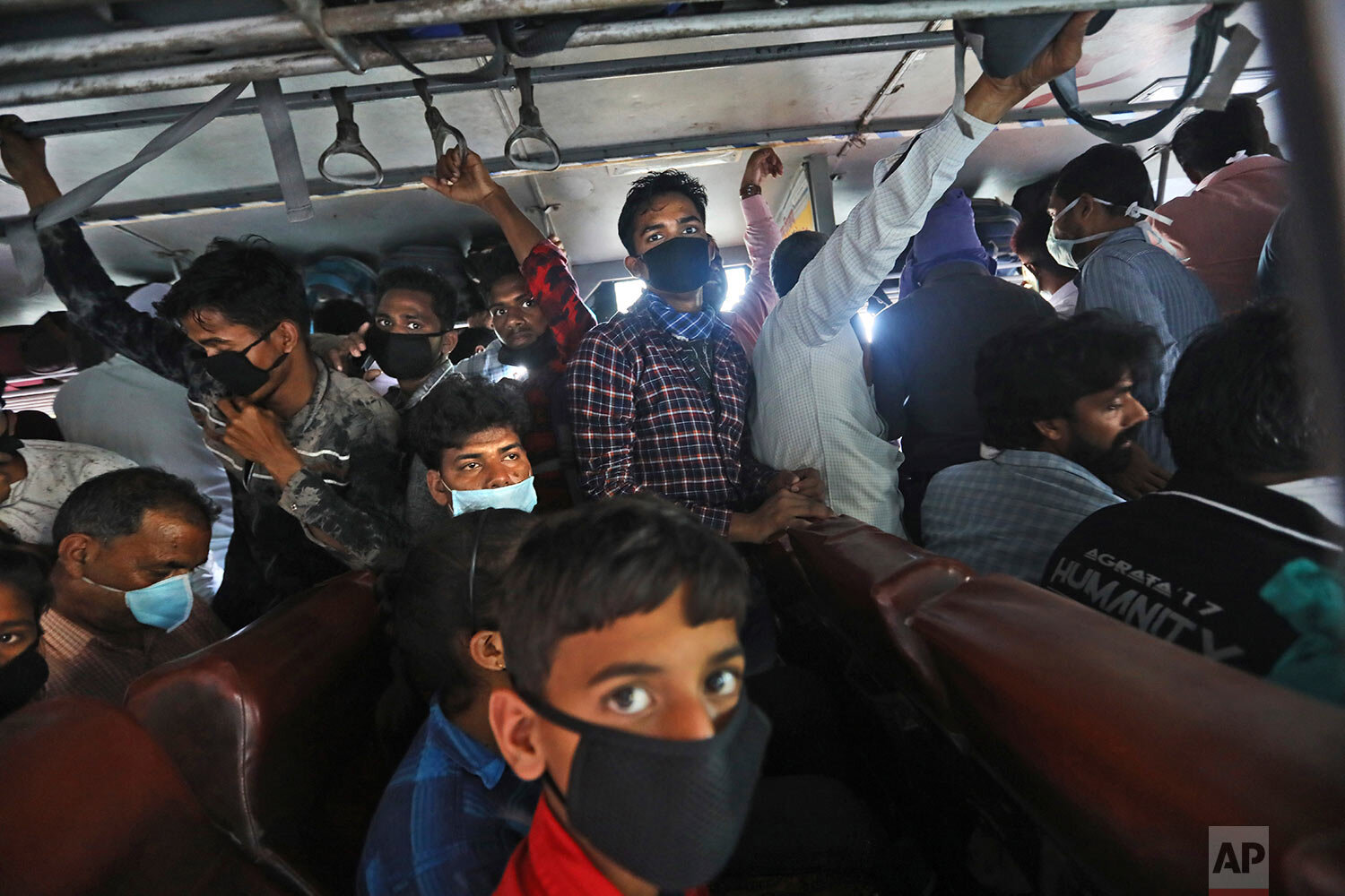  Migrant daily wage laborers crowd a bus as they travel to their respective hometowns following a lockdown amid concern over spread of coronavirus in New Delhi, India, Friday, March 27, 2020. (AP Photo/Manish Swarup) 