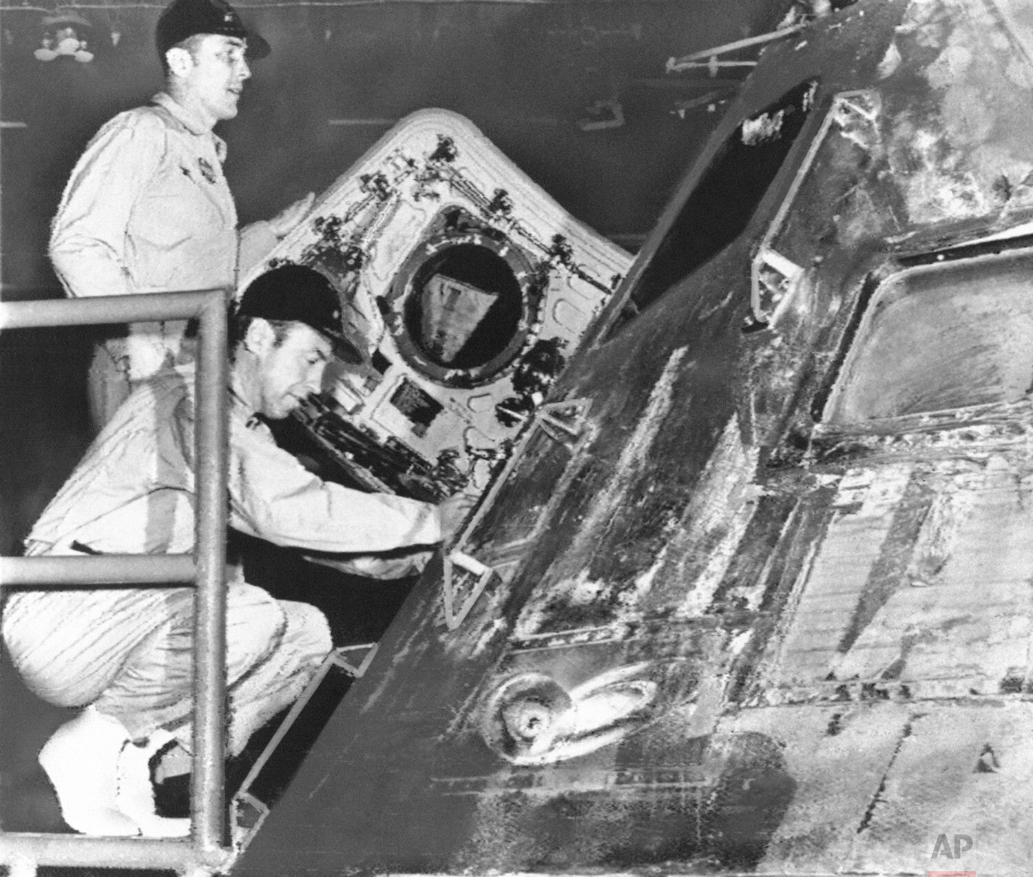  Safely aboard the prime recovery ship, USS Iwo Jima, astronauts James Lovell, squatting, and John Swigert, inspect the Apollo 13 command module that carried them to a safe splashdown in the South Pacific, Friday, April 17, 1970. (AP Photo) 