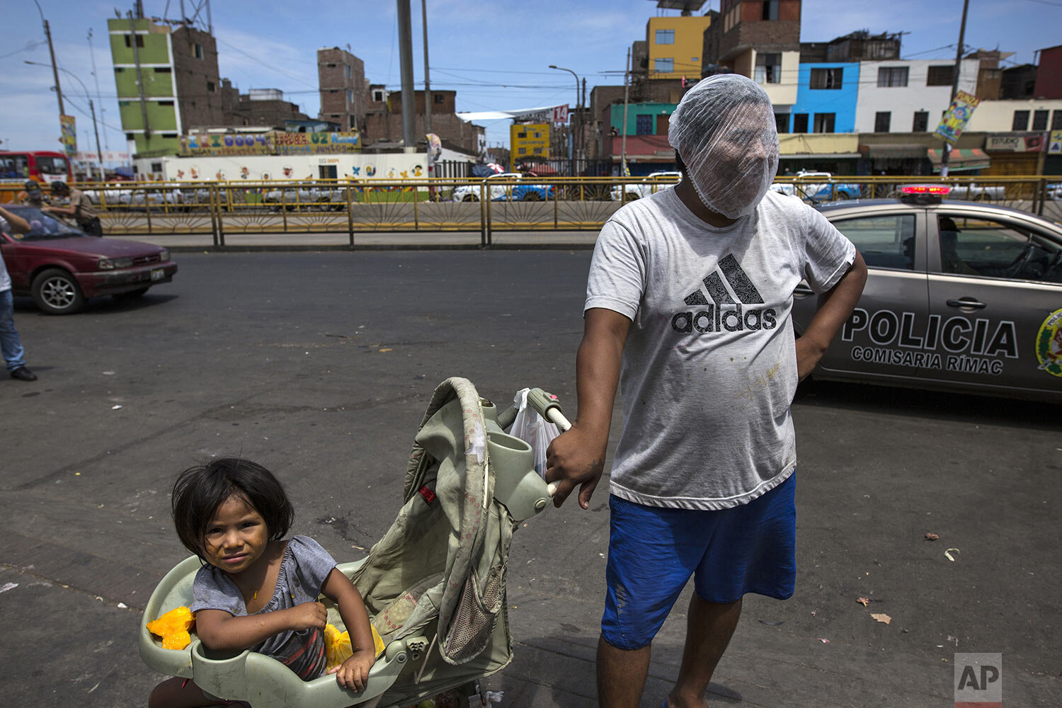  In this March 19, 2020 photo, Luis Mendoza jokingly dons a hair net over his face given to him by a group handing out protective gear outside a popular market where he has come to beg for food with his 2-year-old daughter Alejandra, in Lima, Peru. Ê