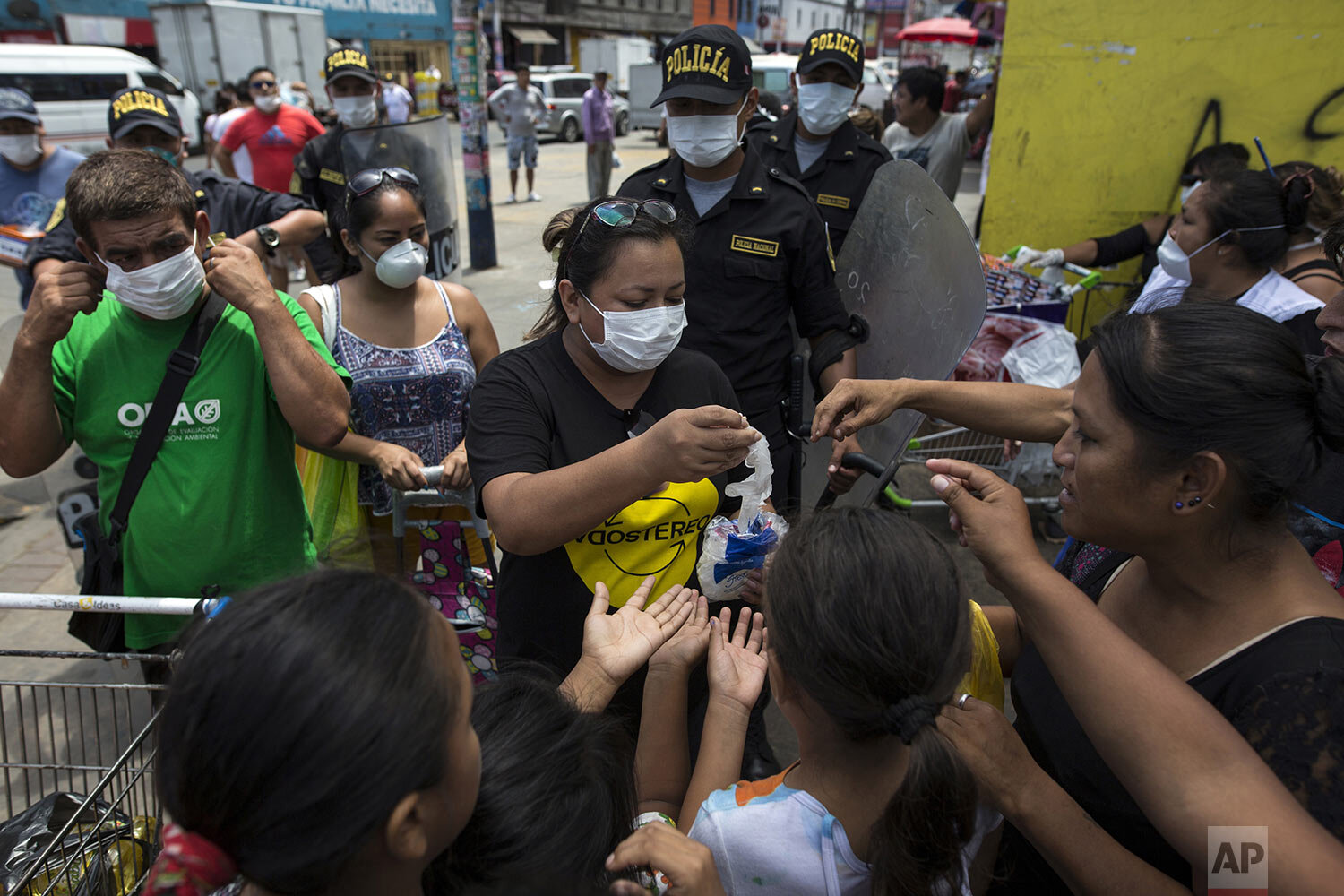  In this March 19, 2020 photo, Cesar Alegre, far left, and fellow residents who share a sprawling rundown house, receive free protective gear to help curb the spread of the new coronavirus, outside a popular food market in Lima, Peru. (AP Photo/Rodri