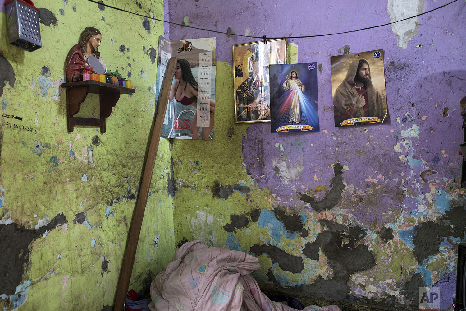  This March 26, 2020 photo shows the paint peeling on the cracked walls of Santos Escobar’s small room and his few belongings in a crumbling building nicknamed “Luriganchito,” after the country’s most populous prison, where its residents have stories