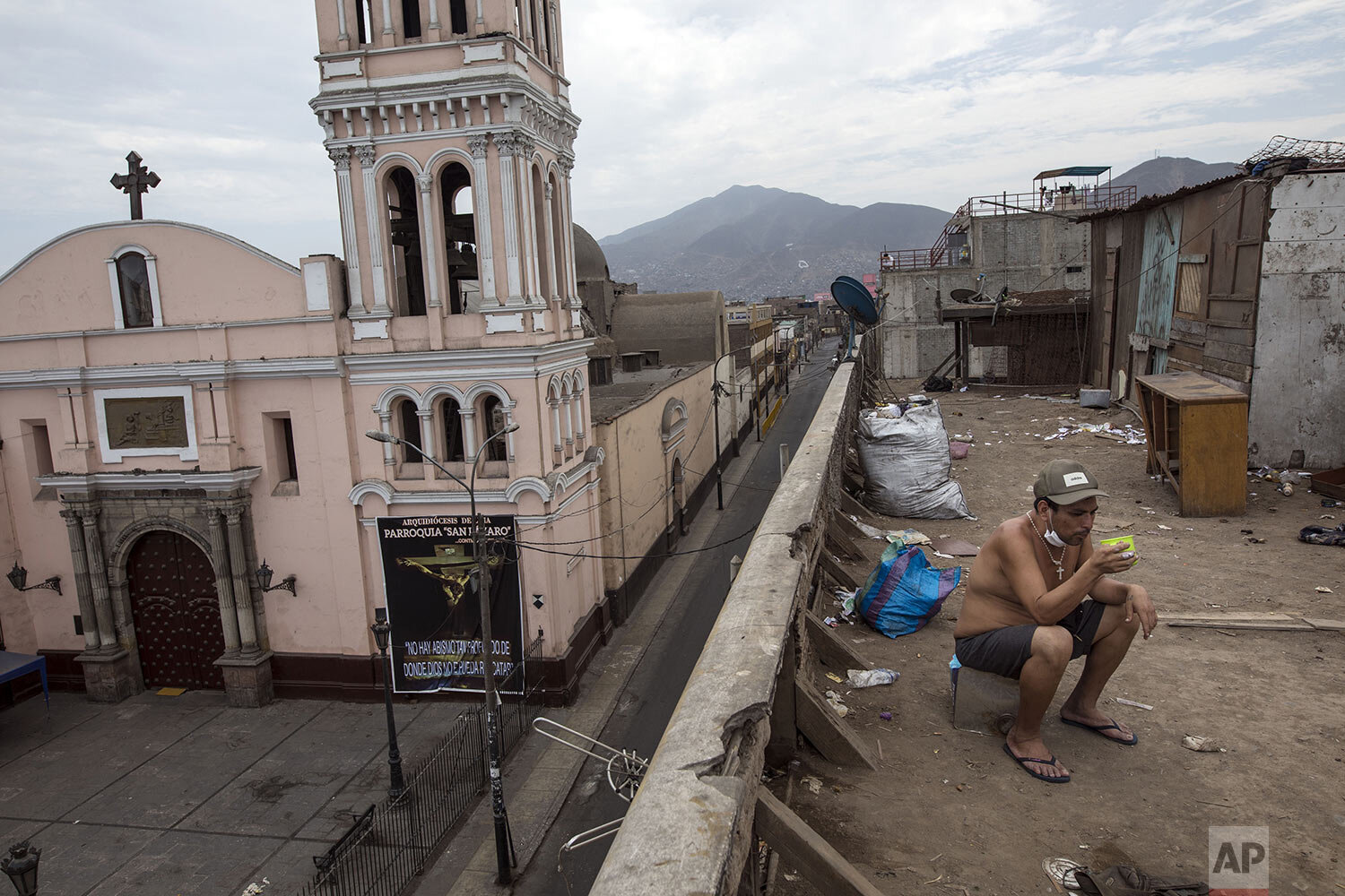  In this April 5, 2020 photo, Raul Coyantes eats his breakfast on the rooftop of the deteriorating building nicknamed "Luriganchito," after the country's most populous prison, where he rents a room, in Lima, Peru. Located just a few blocks from the p