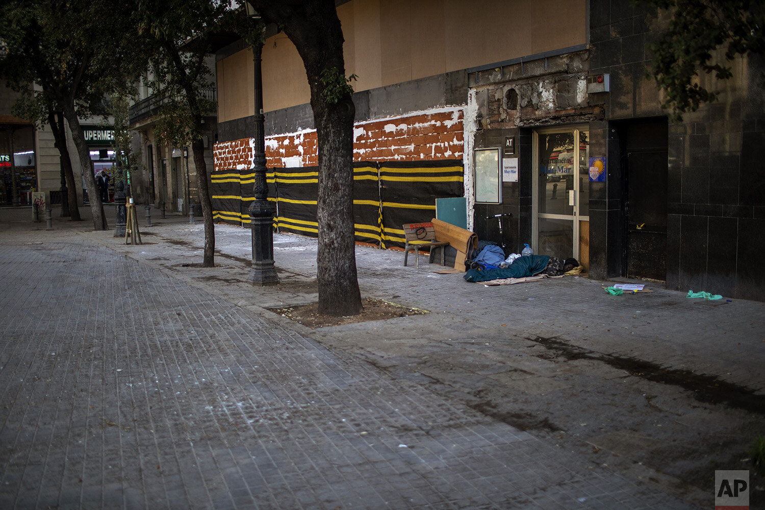  In this Thursday, March 19, 2020, a man of sub-Saharan Africa sleeps in an empty street in downtown Barcelona, Spain. (AP Photo/Emilio Morenatti) 