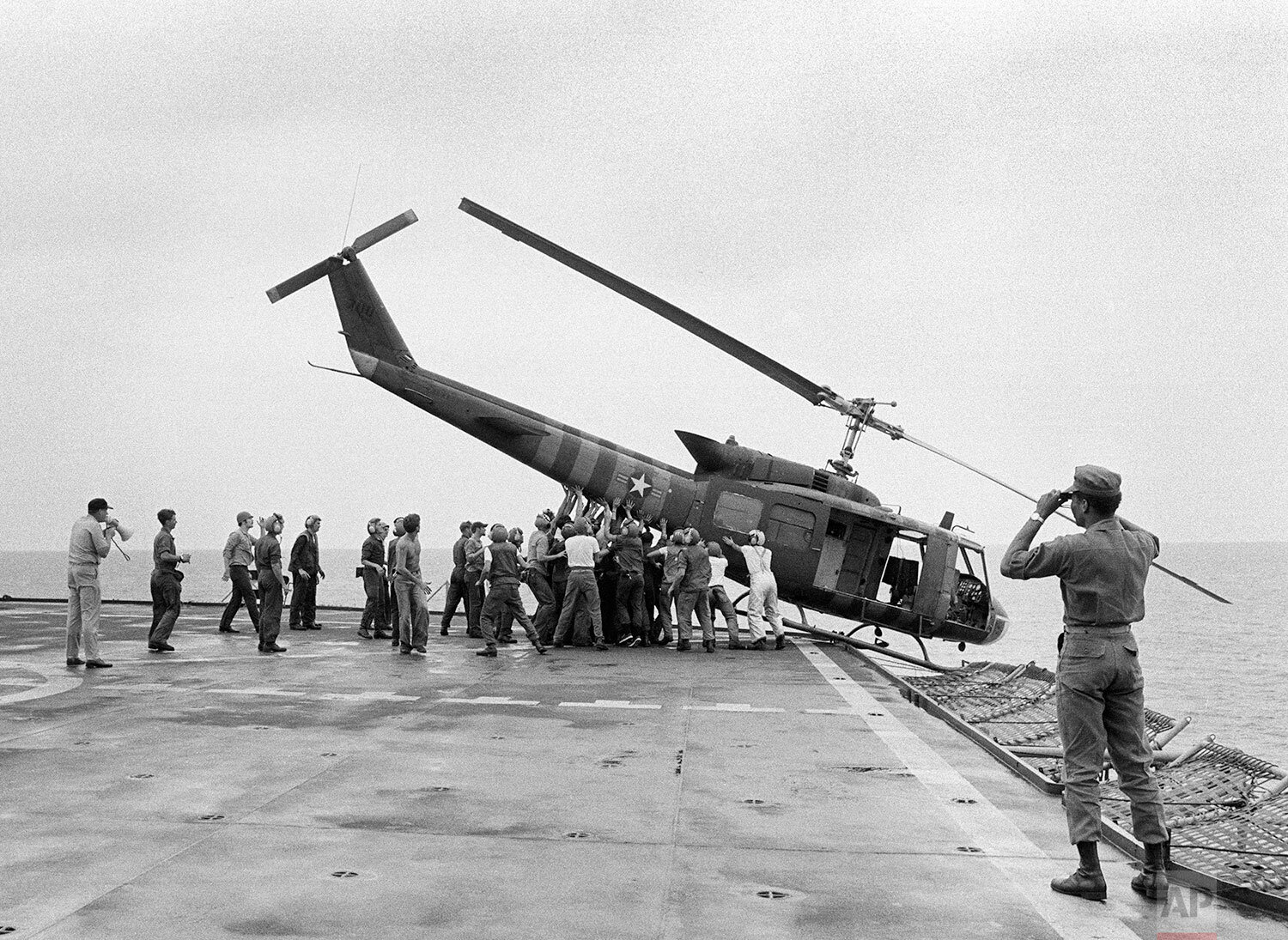  U.S. Navy personnel aboard the USS Blue Ridge push a helicopter into the sea off the coast of Vietnam in order to make room for more evacuation flights from Saigon, Tuesday, April 29, 1975.  The helicopter had carried Vietnamese fleeing Saigon as No