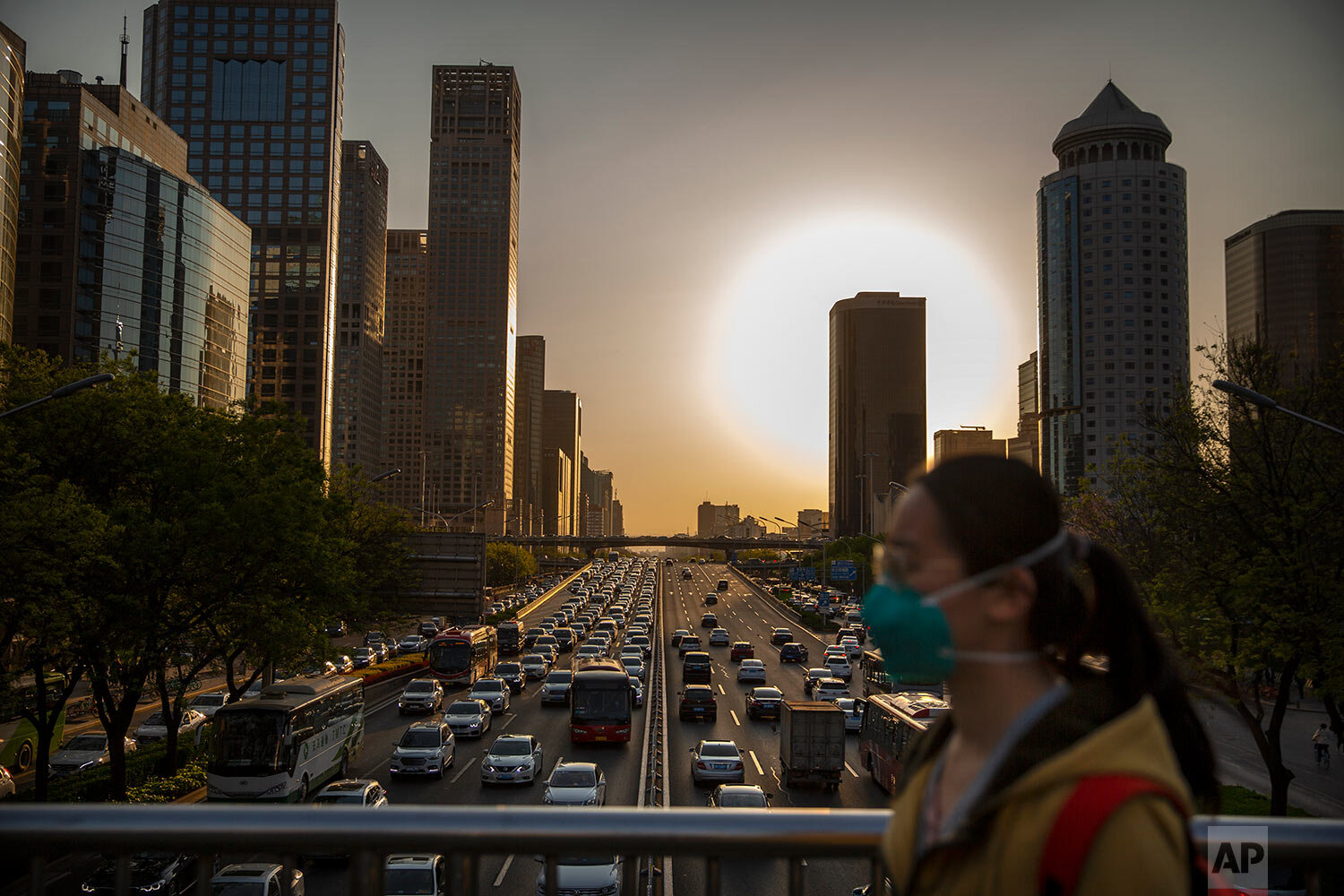  A woman wears a face mask to protect against the spread of the new coronavirus as she walks across a pedestrian bridge in Beijing, Thursday, April 23, 2020. (AP Photo/Mark Schiefelbein) 
