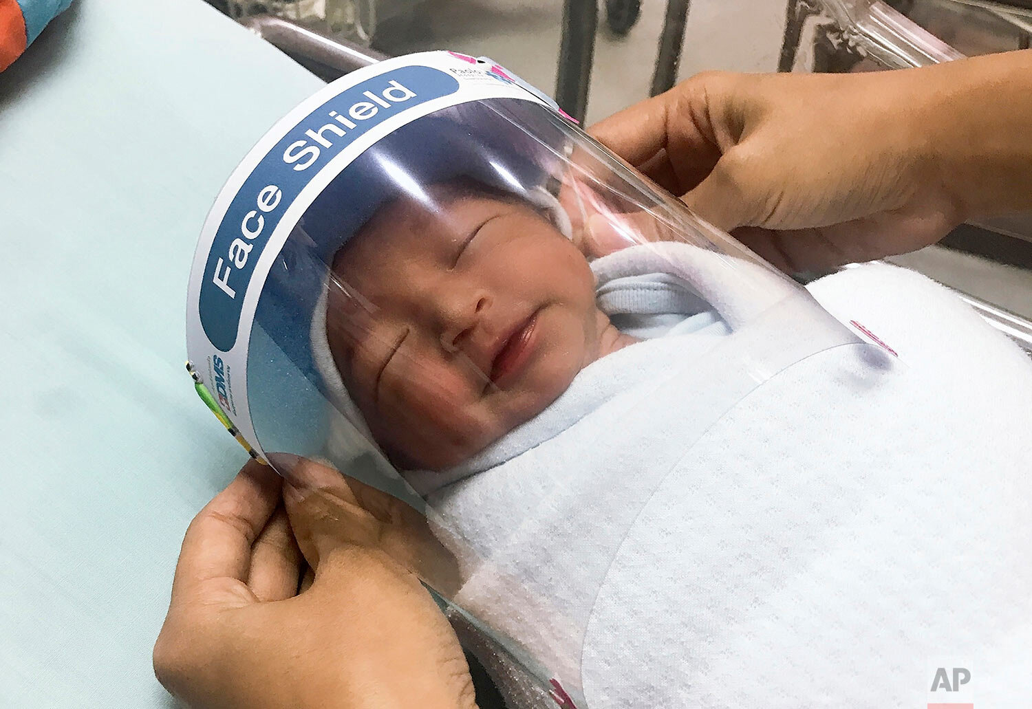  In this photo released by Paolo Hospital Samutprakarn, a nurse adjusts tiny face shield for a newborn baby to protect from new coronavirus at the newborn nursery of the hospital in Samutprakarn province, central Thailand, Friday, April 3, 2020.  (Pa