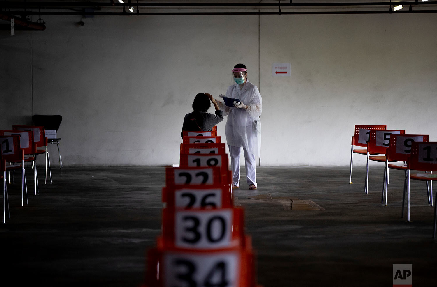  A nurse in protective clothing takes notes from a woman with symptoms of new coronavirus at a carpark that turned into a COVID-19 infection screening center at Chulalongkorn University health service center in Bangkok, Thailand, Wednesday, April 1, 
