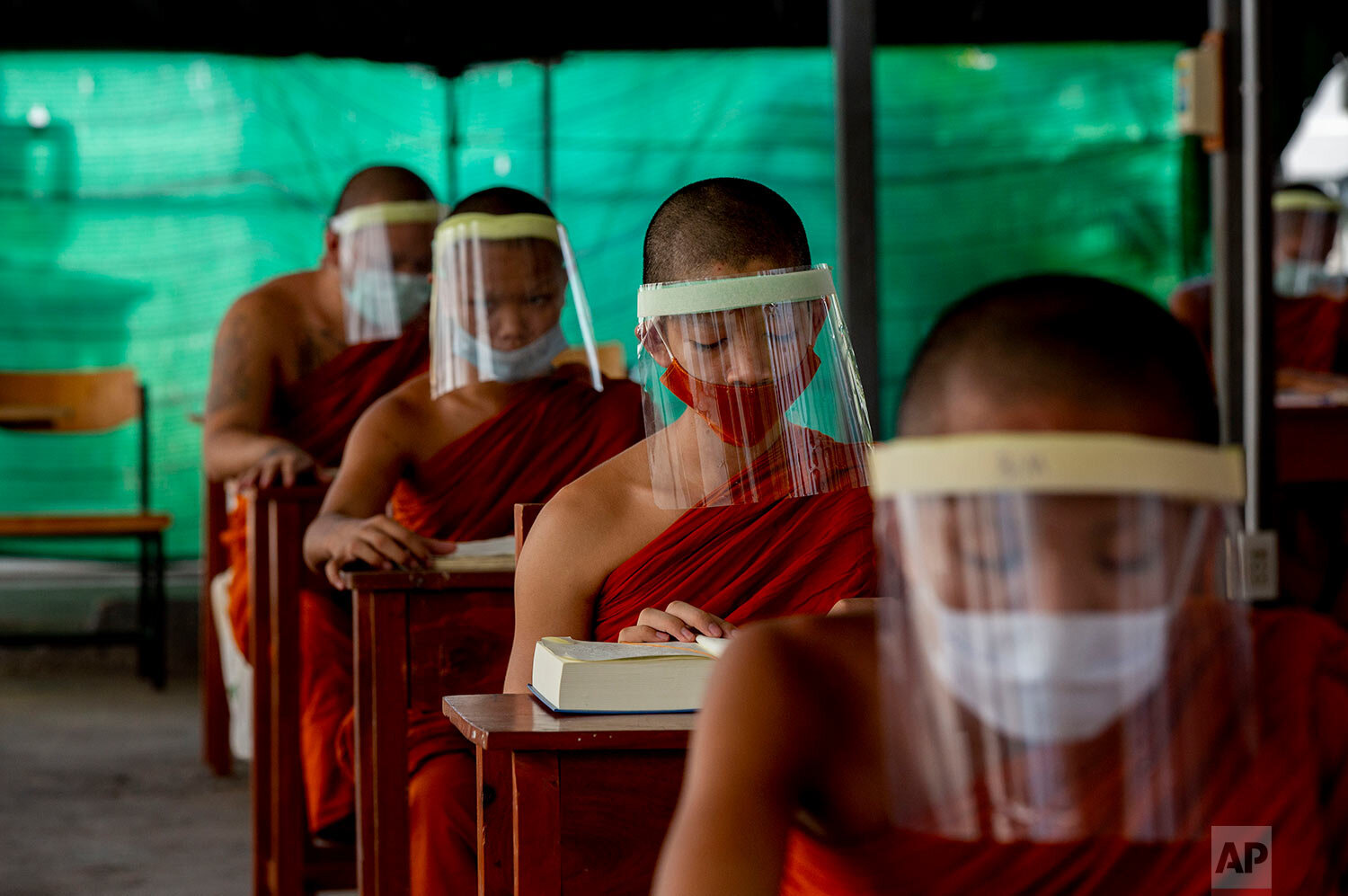  Novice Buddhist monks with protective masks and face shields, seated maintaining social distancing participate in a religious class at Molilokayaram Educational Institute in Bangkok, Thailand, Wednesday, April 15, 2020.  (AP Photo/Gemunu Amarasinghe