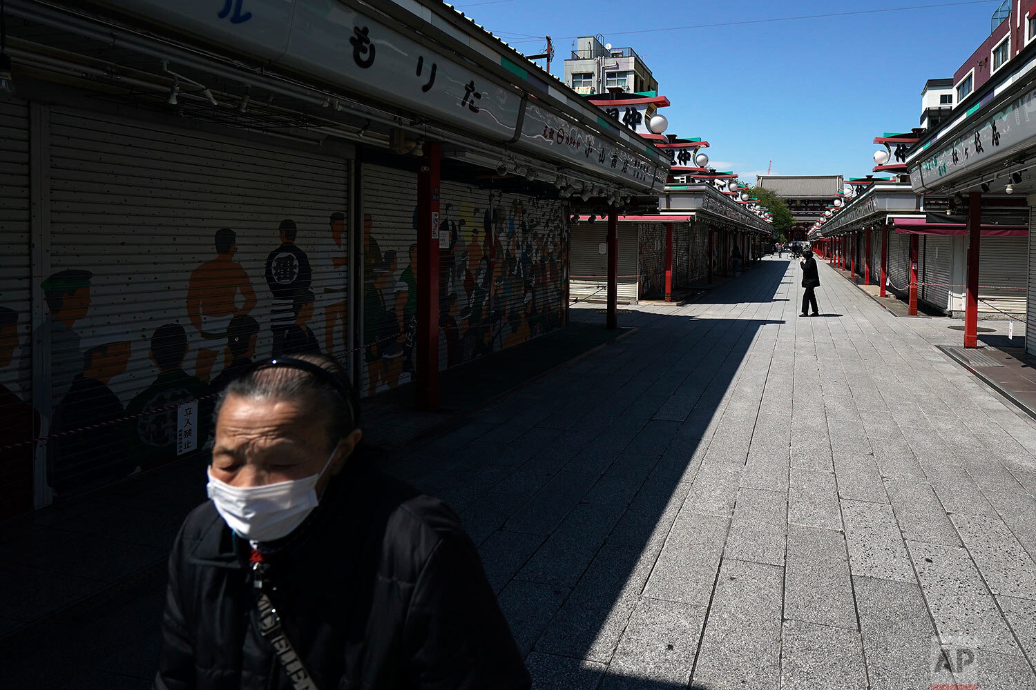  A woman wearing a mask to help stop the spread of the new coronavirus walks at usually crowded shopping arcade near Sensoji Temple in Tokyo Thursday, April 23, 2020. (AP Photo/Eugene Hoshiko) 