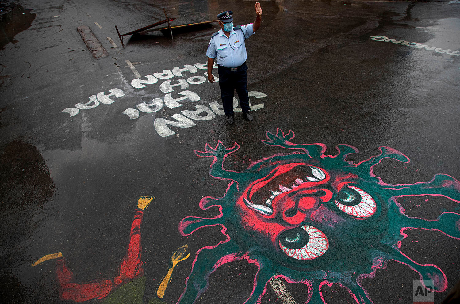  An Indian traffic policeman stands next to an artwork displayed on a road to create awareness about coronavirus during lockdown in Gauhati, India, Wednesday, April 15, 2020. (AP Photo/Anupam Nath) 