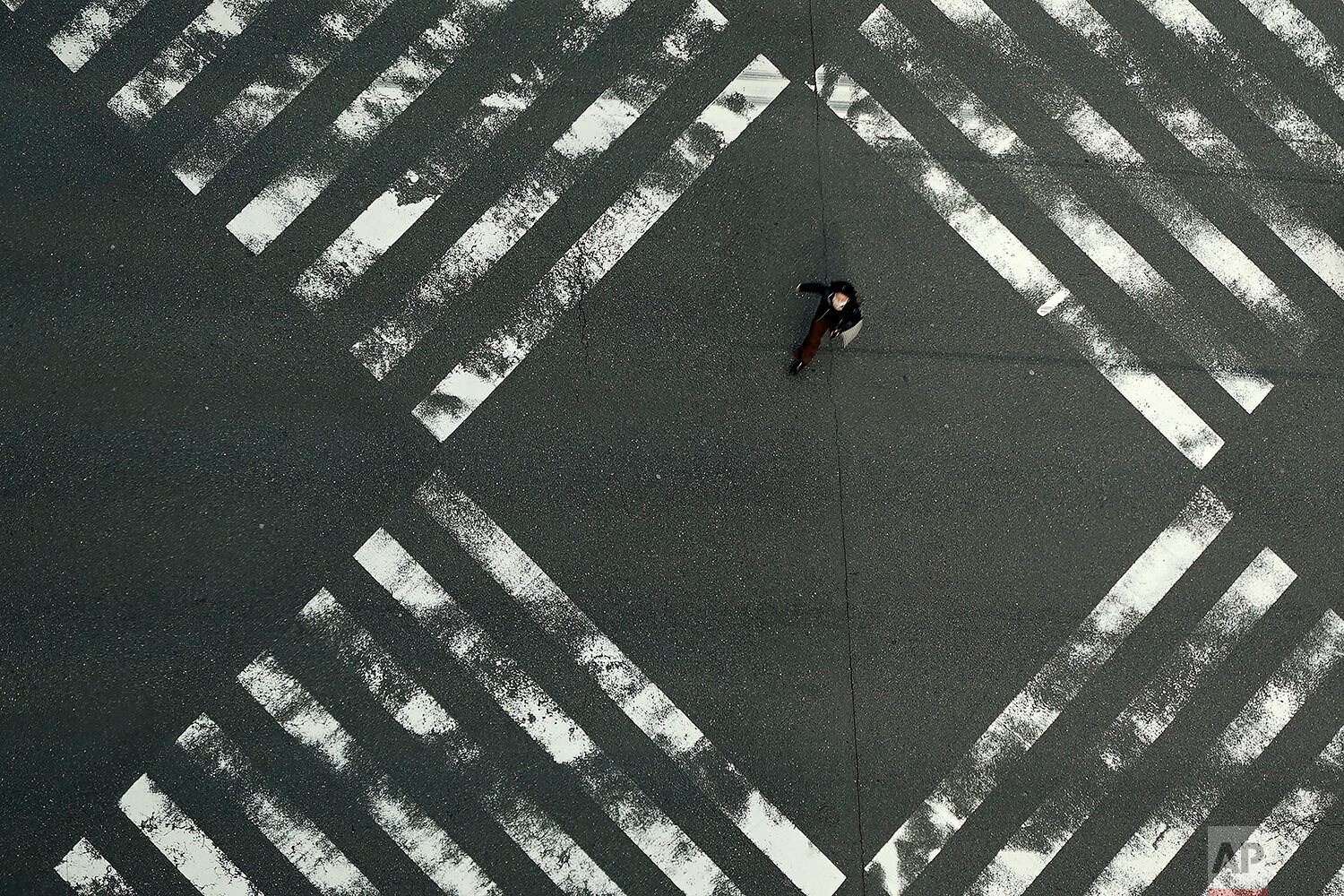  A woman walks through an empty pedestrian crossing in the Ginza shopping district Friday, April 3, 2020, in Tokyo.  (AP Photo/Eugene Hoshiko) 