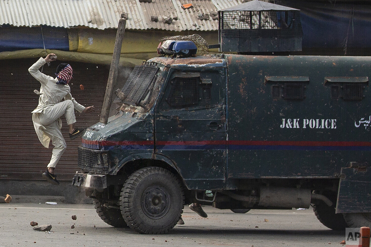  A masked Kashmiri protester jumps on the bonnet of an armored vehicle of Indian police as he throws stones at it during a protest in Srinagar, Indian controlled Kashmir, May 31, 2019. (AP Photo/Dar Yasin) 