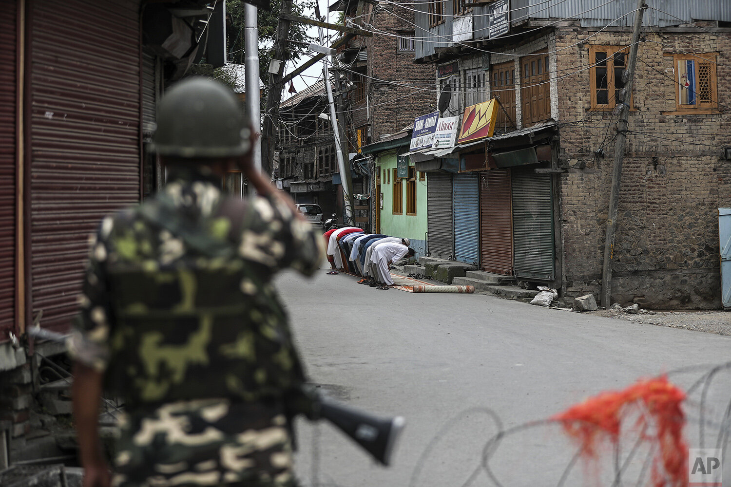  A Indian paramilitary soldier stands guard as Kashmiri Muslims offer Friday prayers on a street outside a local mosque during curfew like restrictions in Srinagar, India, Aug. 16, 2019. (AP Photo/Mukhtar Khan) 