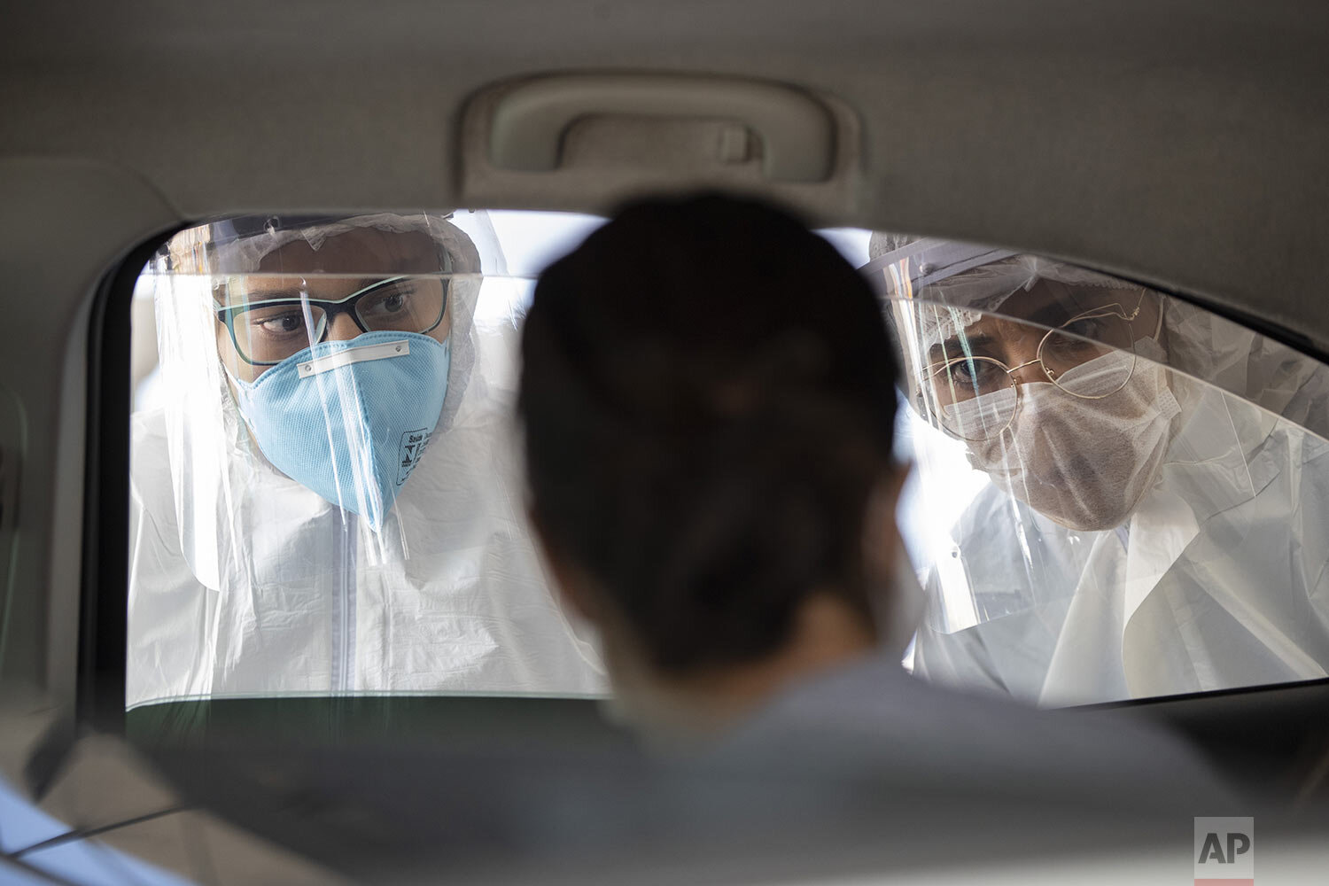  Medical workers in protective gear peer into a car to check if commuters have COVID-19 symptoms in Guarulhos on the outskirts of Sao Paulo, Brazil, Monday, March 30, 2020. (AP Photo/Andre Penner) 