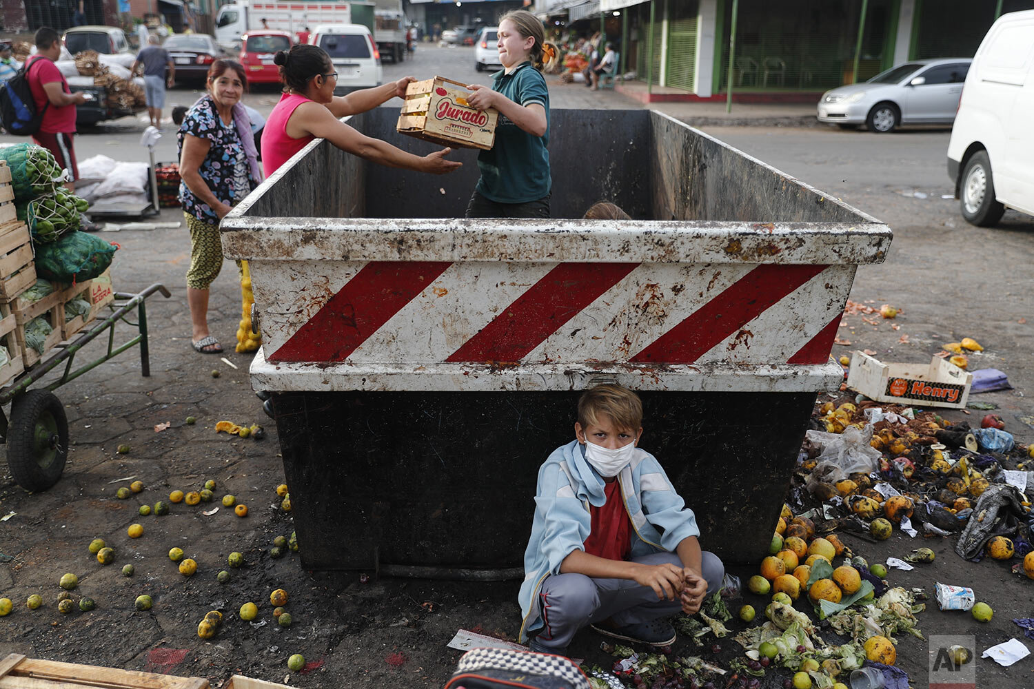  Fabian Ramirez, 11, scavenges a trash container for vegetables with his family at the "Mercado de Abasto," a market for vendors, during the fourth week of a quarantine to help contain the spread of the new coronavirus in Asuncion, Paraguay, Thursday