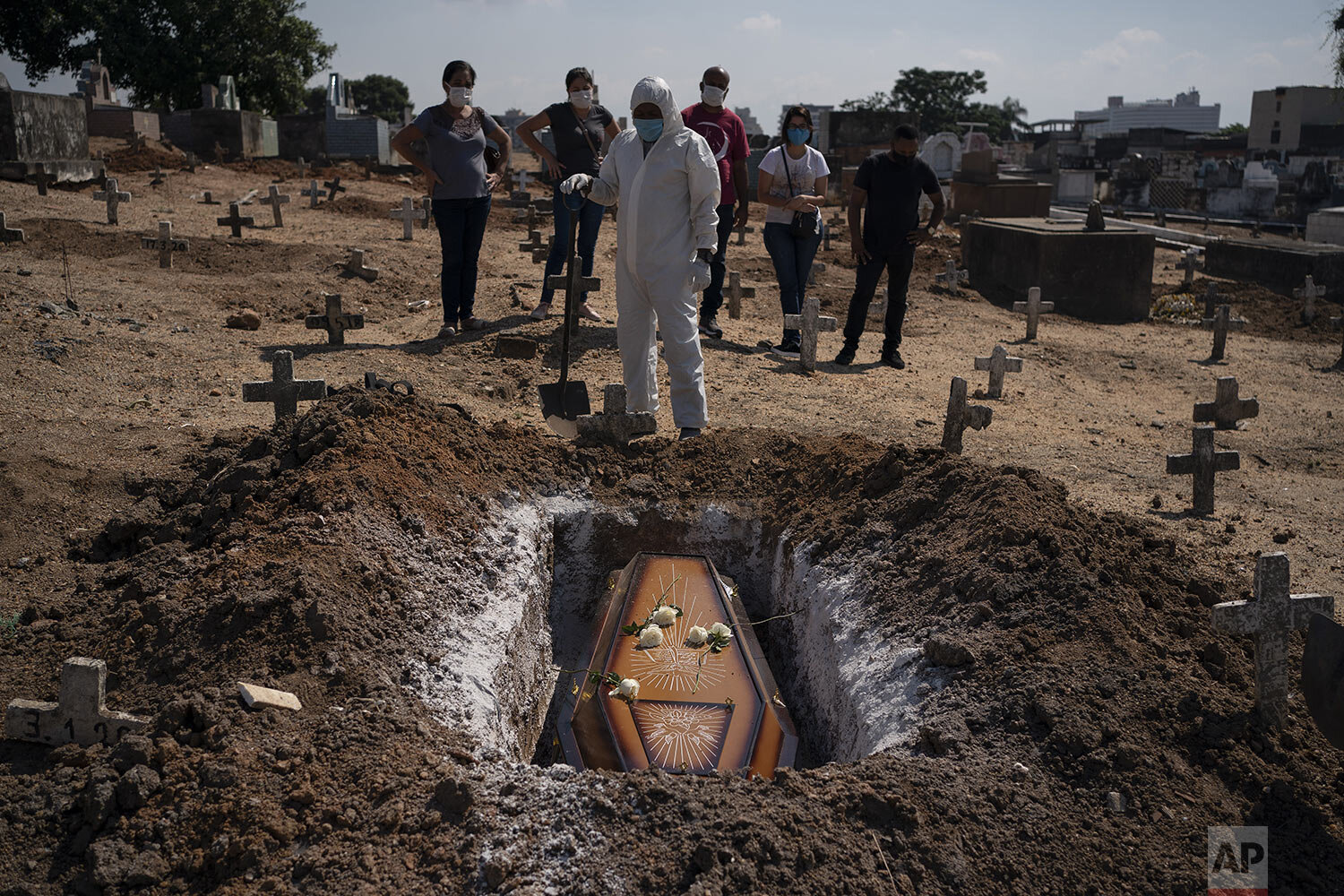  A cemetery worker stands over the remains of Edenir Rezende Bessa, who is suspected of dying of COVID-19, as relatives attend her burial in Rio de Janeiro, Brazil, Wednesday, April 22, 2020. After visiting 3 primary care health units, she was accept