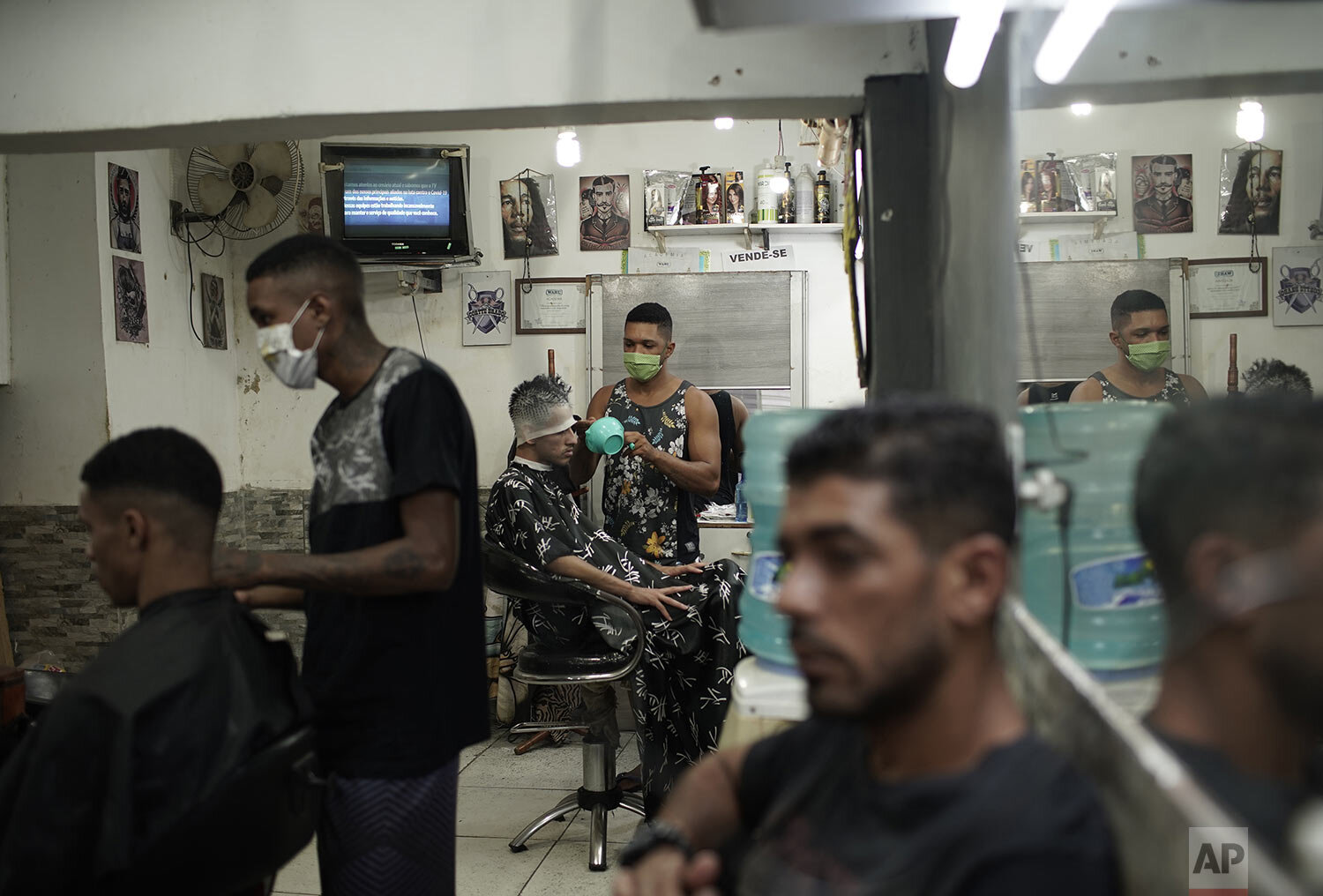  Haircutters, wearing protective face masks as a precaution against the spread of the new coronavirus, attend to clients in a barbershop in the Mandela favela of Rio de Janeiro, Brazil, April 21, 2020. (AP Photo/Silvia Izquierdo) 