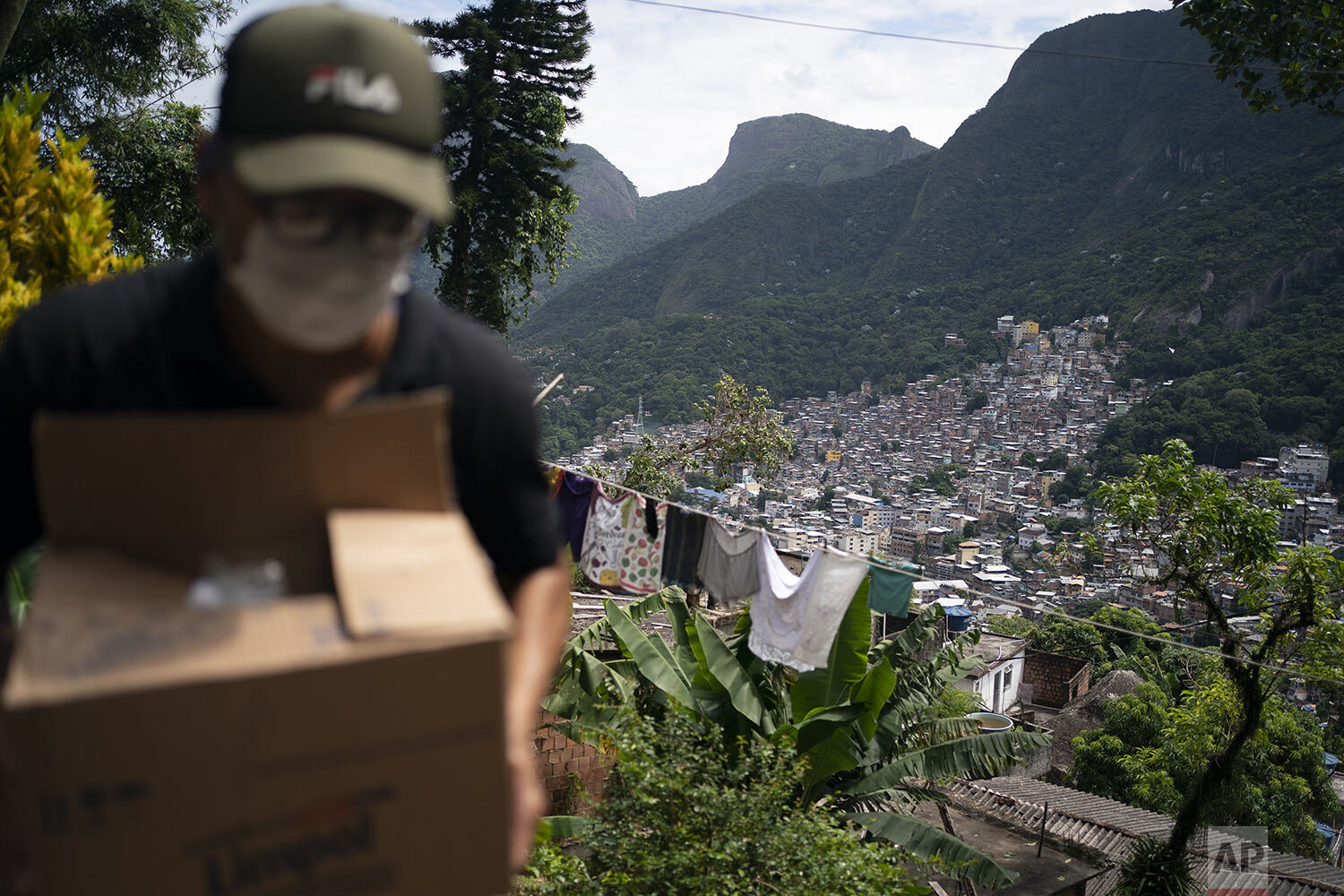  A local volunteer carries a package with soap and detergent to be distributed to residents in an effort to curb the spread of the new coronavirus, in the Rocinha favela of Rio de Janeiro, Brazil, March 24, 2020. (AP Photo/Leo Correa) 