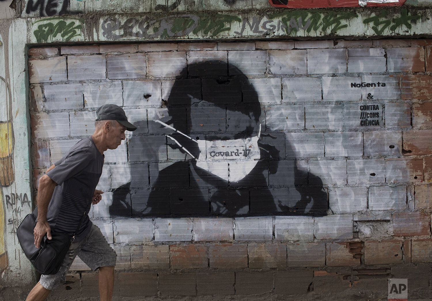  A man walks past a wall emblazoned with a mural depicting Brazil's President Jair Bolsonaro putting on a protective face mask with the Portuguese word for ÒcowardÓ written on it, in Rio de Janeiro, Brazil, April 7, 2020. (AP Photo/Silvia Izquierdo) 