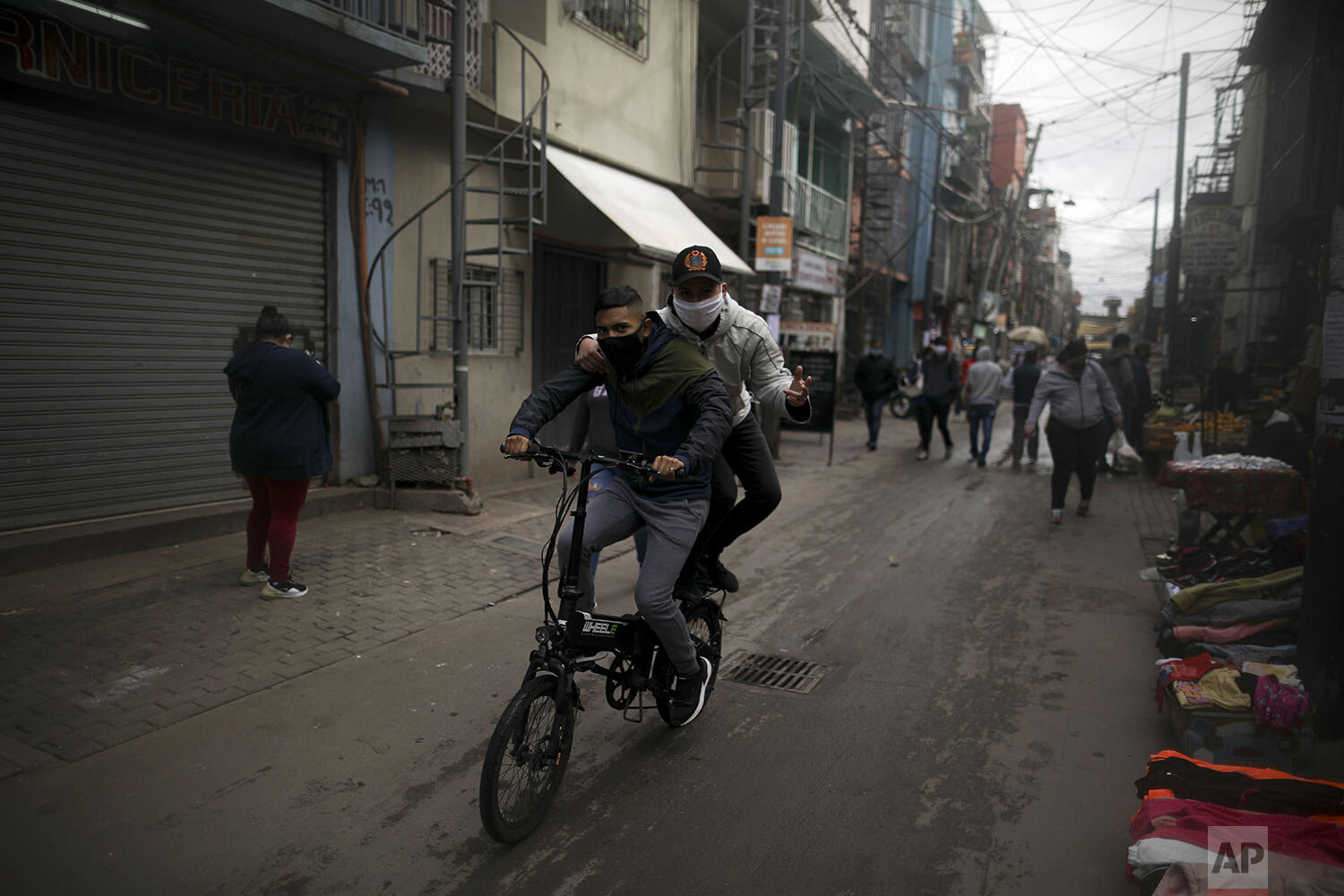 Youths ride a bicycle through "Villa 31" in Buenos Aires, Argentina, Wednesday, May 6, 2020. (AP Photo/Natacha Pisarenko) 