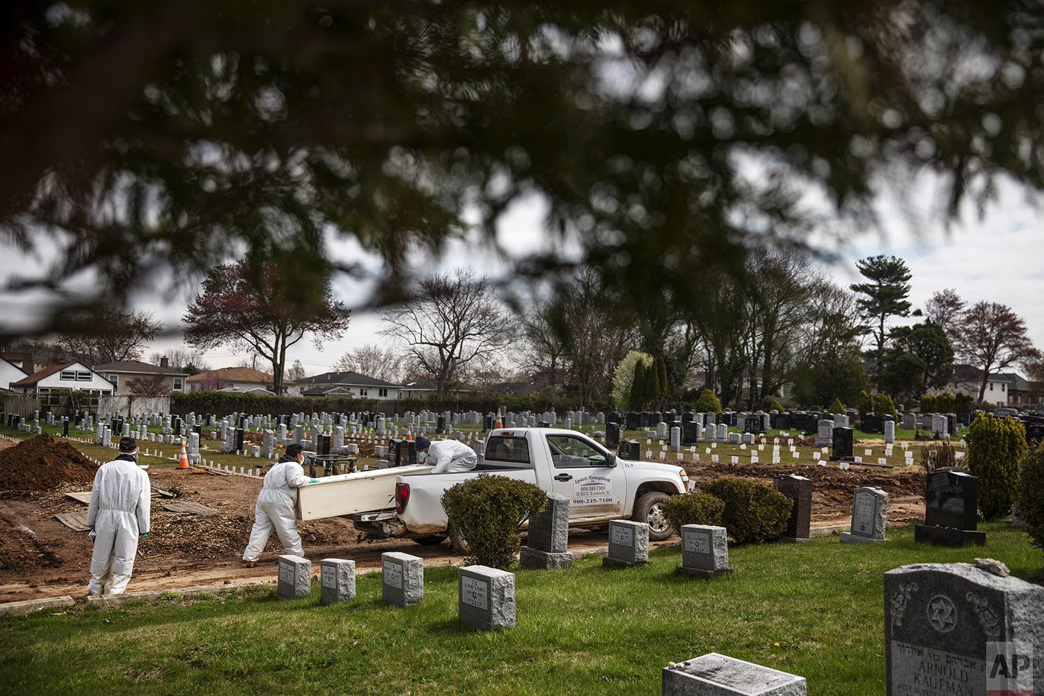  Rabbi Shmuel Plafker, left, watches as a casket is brought for burial at Mount Richmond Cemetery in the Staten Island borough of New York, Wednesday, April 8, 2020. Plafker looks at the trees in bloom and the grass sprouting and finds spring???s sig