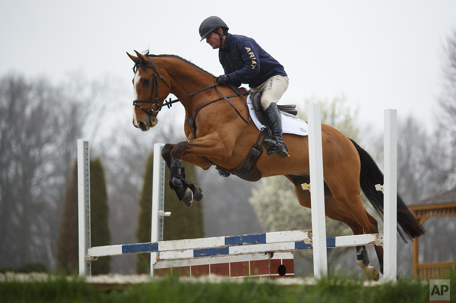 Phillip Dutton, a medal-winning equestrian on the U.S. Olympic team, rides Quasi Cool through a jump during a training session at his farm, Tuesday, March 31, 2020, in West Grove, Pa. (AP Photo/Matt Slocum) 