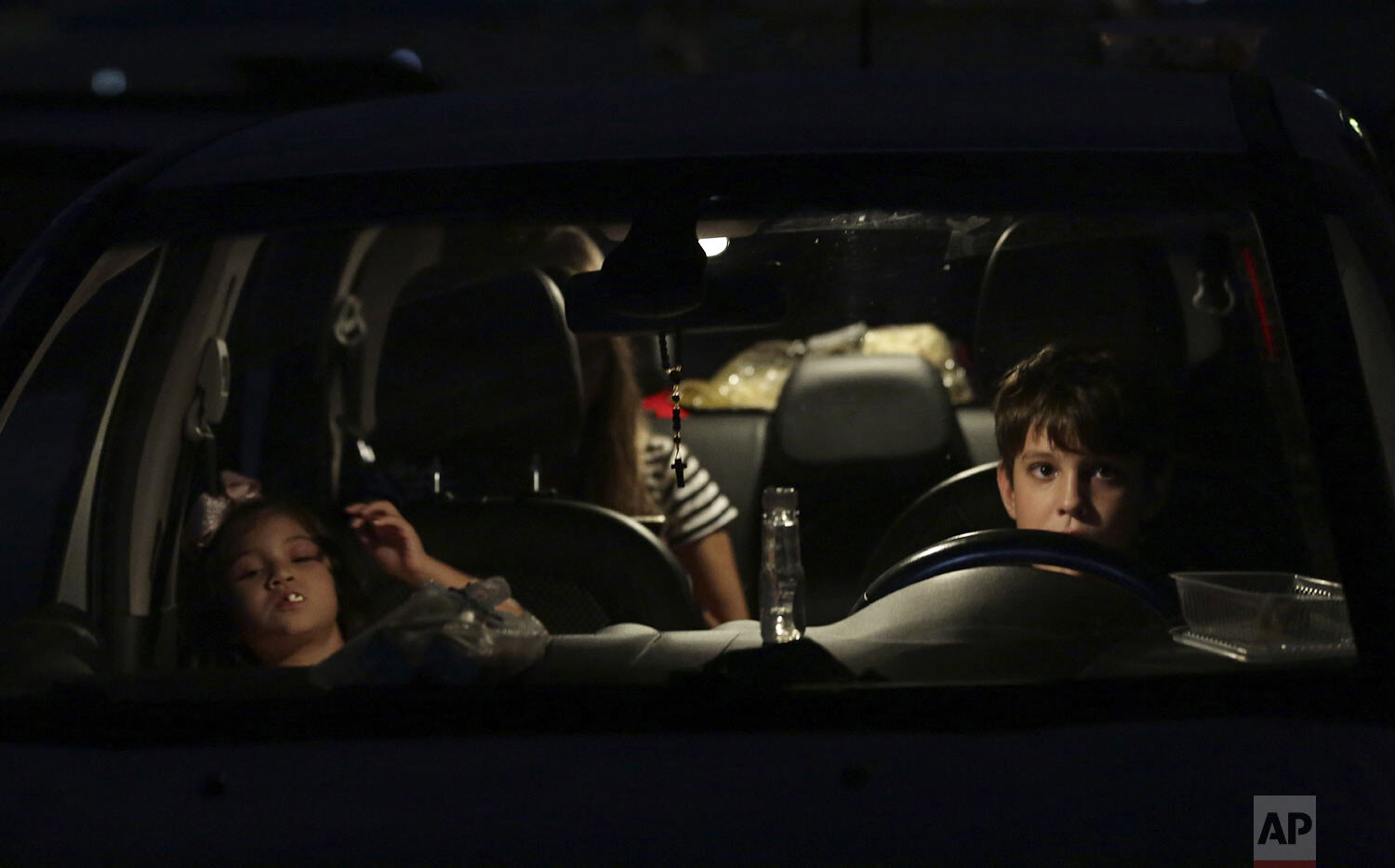  Children watch a film from inside their car at a drive-in movie theater where drivers must leave one space empty between them amid the new coronavirus pandemic in Brasilia, Brazil, Saturday, May 23, 2020. (AP Photo/Eraldo Peres) 