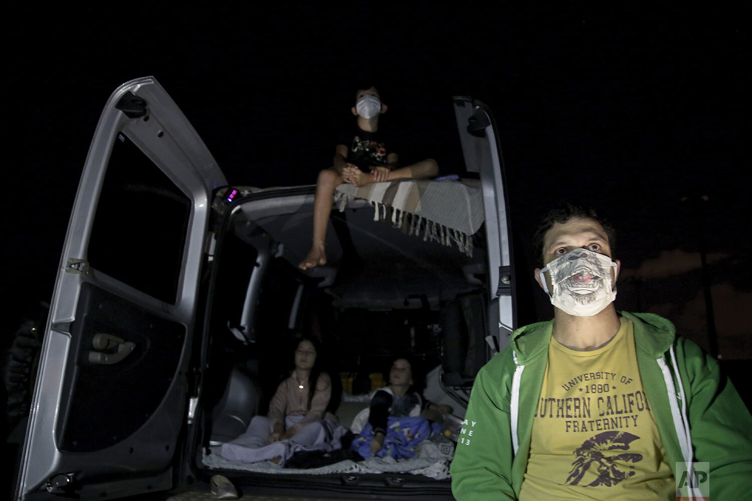  Eduardo Cavalcanti and his children watch a film at a drive-in movie theater where drivers must leave one space empty between them amid the new coronavirus pandemic in Brasilia, Brazil, Wednesday, May 13, 2020. (AP Photo/Eraldo Peres) 