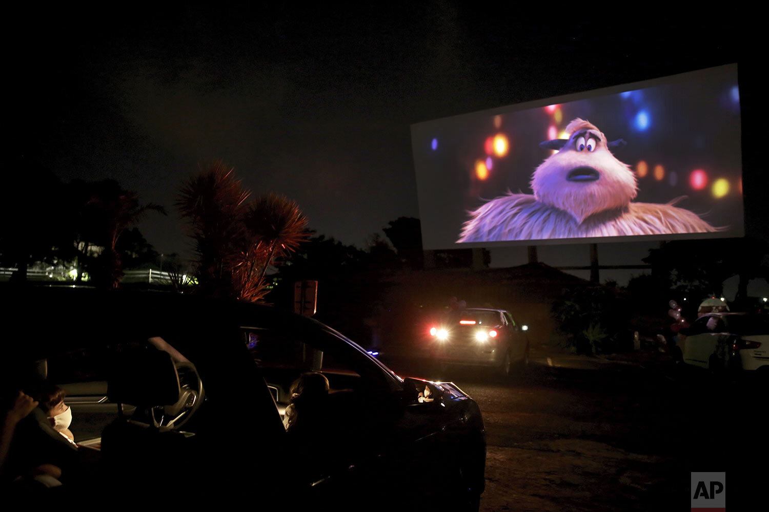  A family wearing face masks watches a movie at a drive-in where drivers must leave one space empty between them amid the spread of the new coronavirus in Brasilia, Brazil, Wednesday, May 13, 2020. (AP Photo/Eraldo Peres) 