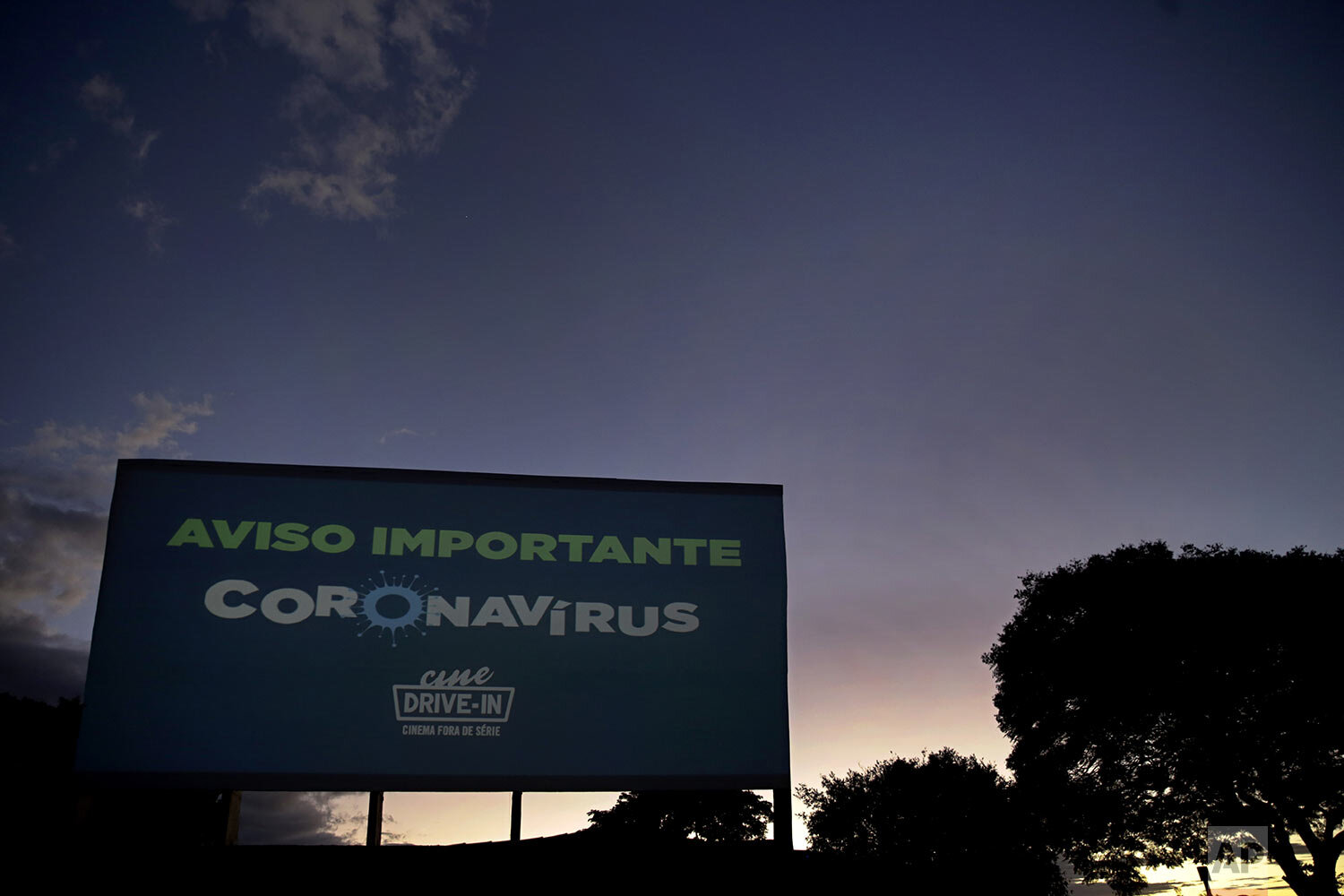  A sign that flashes different warnings about coronavirus, in Portuguese, stands tall at a drive-in movie theater where drivers must leave one space empty between them in Brasilia, Brazil, Saturday, May 23, 2020. (AP Photo/Eraldo Peres) 