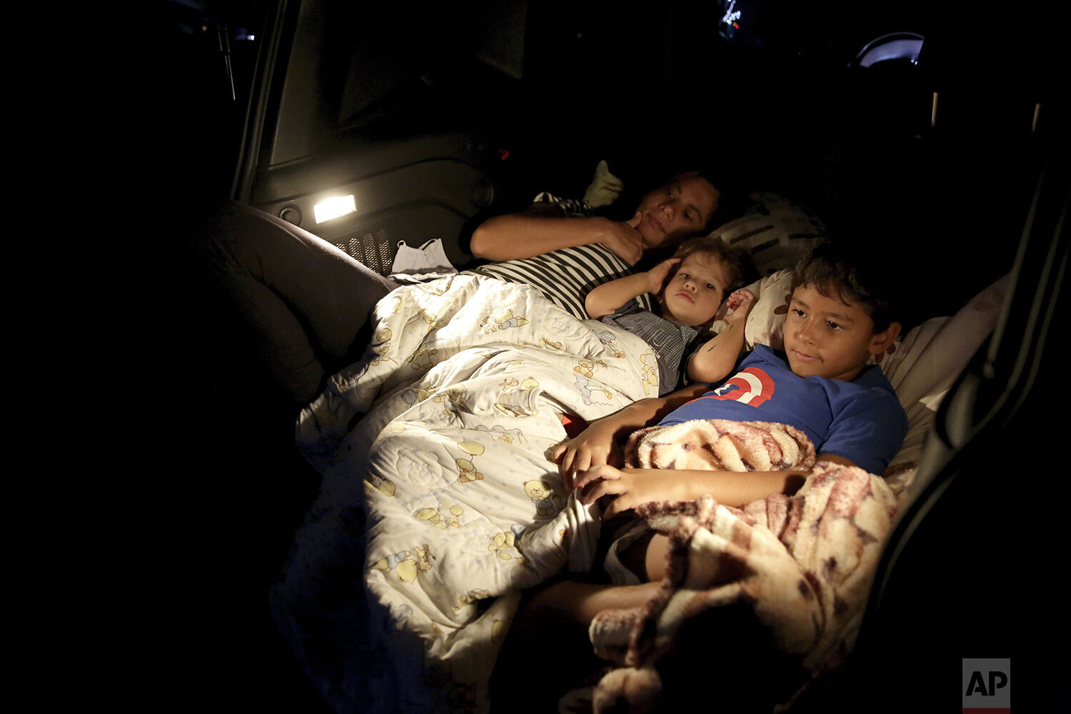  Ana Paula Santos and her children watch a movie from inside their car at a drive-in movie theater where drivers must leave one space empty between them in Brasilia, Brazil, Wednesday, May 13, 2020. (AP Photo/Eraldo Peres) 