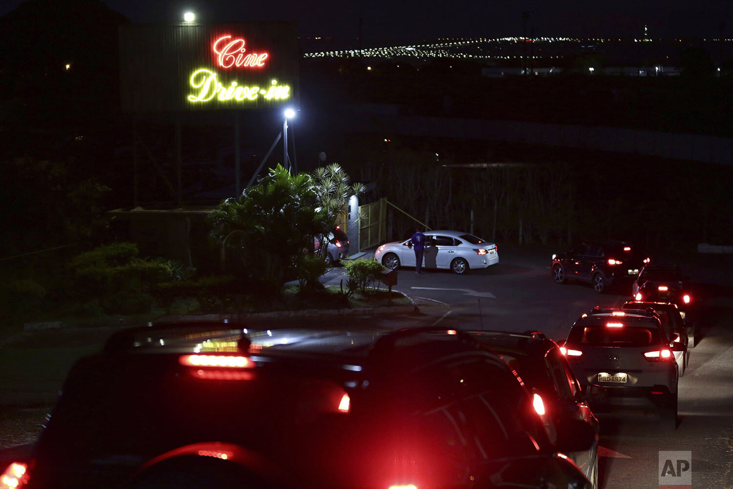  Drivers arrive at the drive-in movie theater where drivers must leave one space empty between them amid the new coronavirus pandemic in Brasilia, Brazil, Wednesday, May 13, 2020. (AP Photo/Eraldo Peres) 