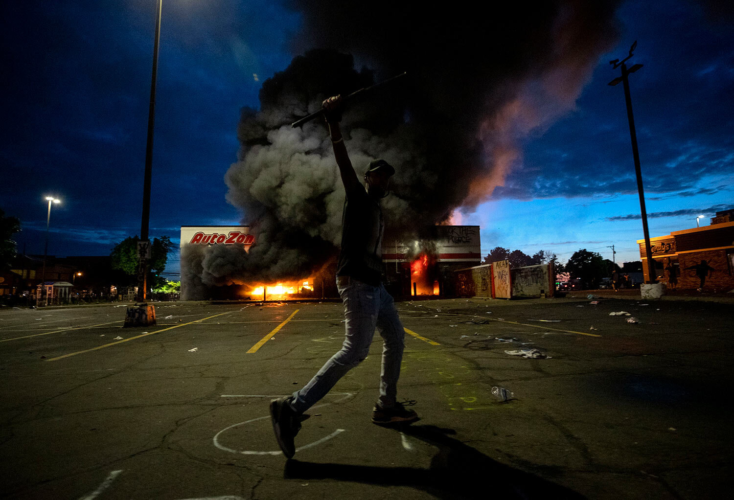  A man poses in the parking lot of an AutoZone store in flames, while protesters hold a rally against the death of George Floyd in Minneapolis on Wednesday, May 27, 2020. (Carlos Gonzalez/Star Tribune via AP) 
