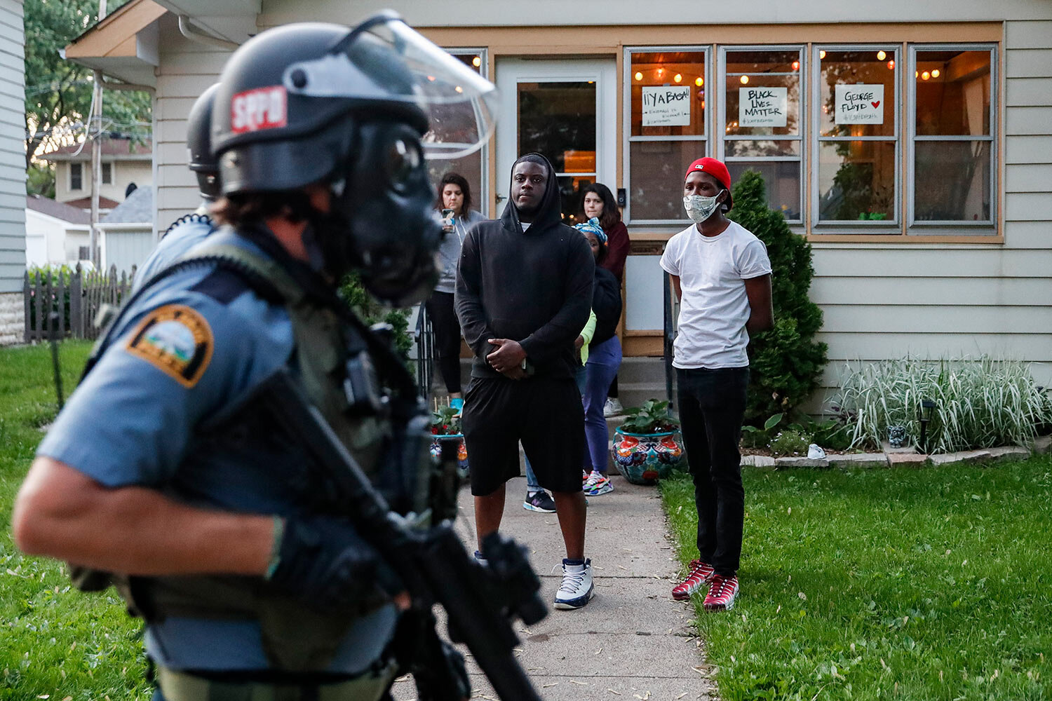  Protestors watch as police in riot gear walk down a residential street, Thursday, May 28, 2020, in St. Paul, Minn. (AP Photo/John Minchillo) 