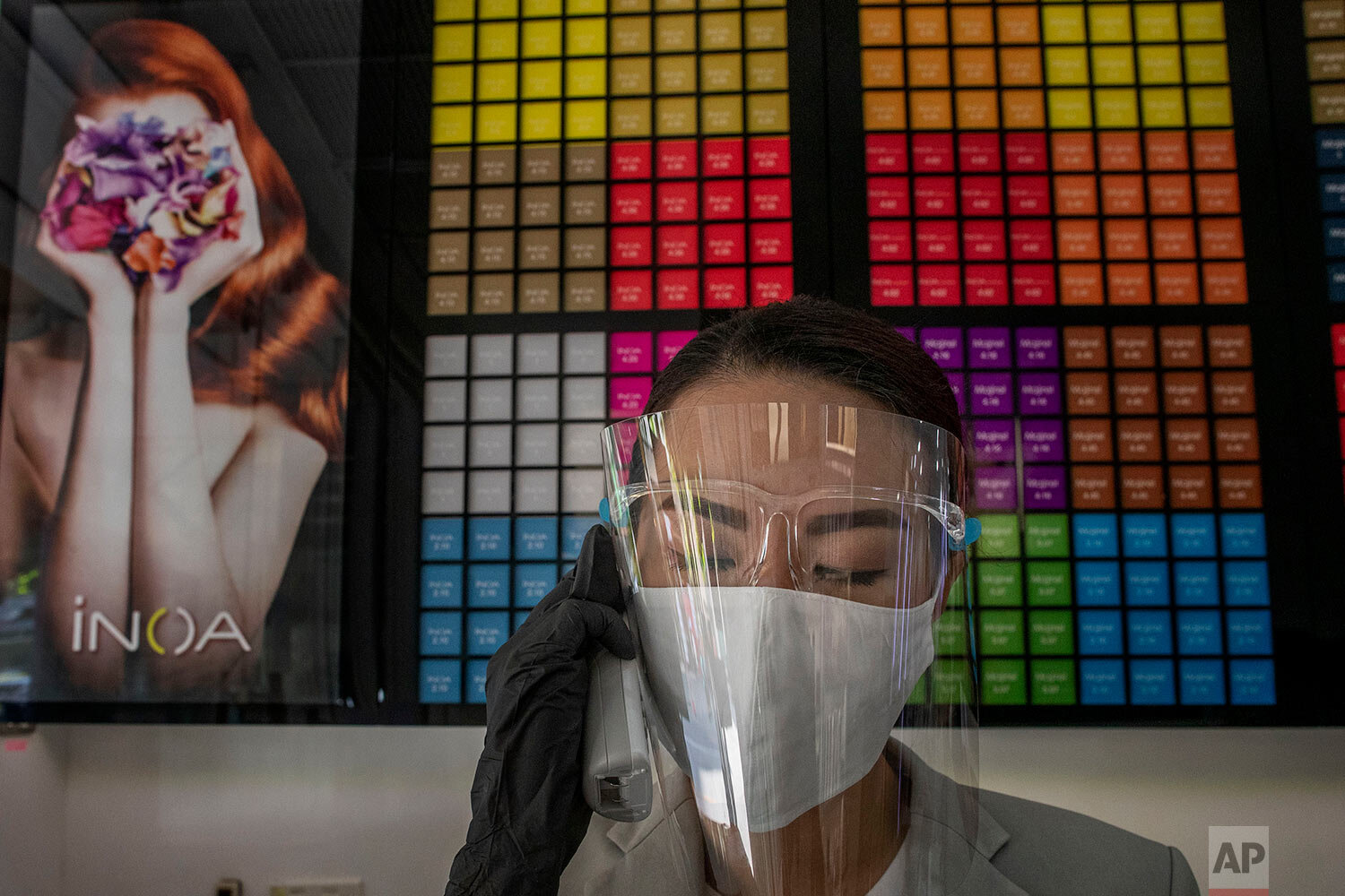  A receptionist with a protective mask and a face shield answers a call at a hair salon in Bangkok, Thailand, Tuesday, May 5, 2020.  (AP Photo/Gemunu Amarasinghe) 