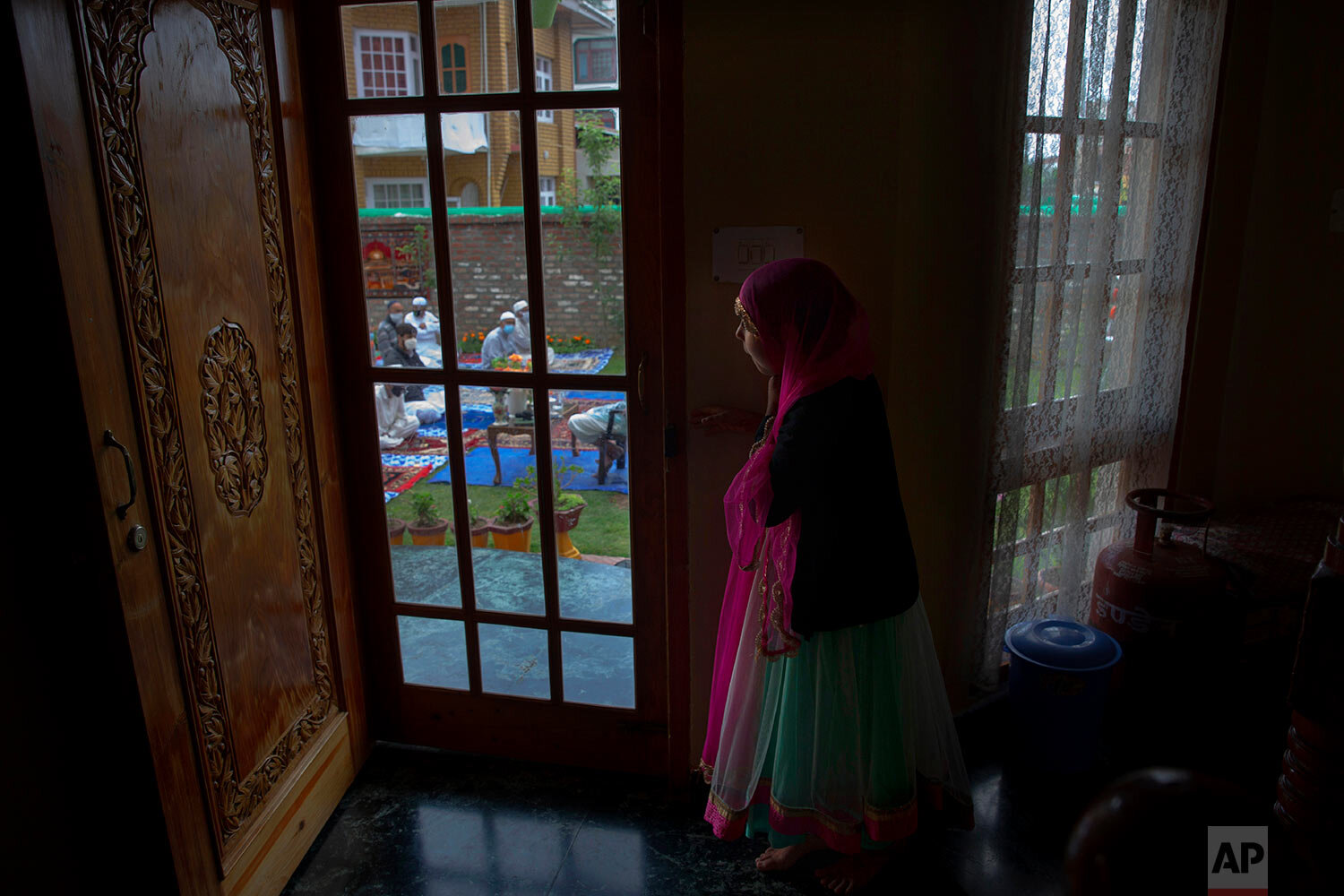  A Kashmiri girl watches from inside her house as men offer Eid prayers in the premises of a residential building in Srinagar, Indian controlled Kashmir, Sunday, May 24, 2020. (AP Photo/Dar Yasin) 