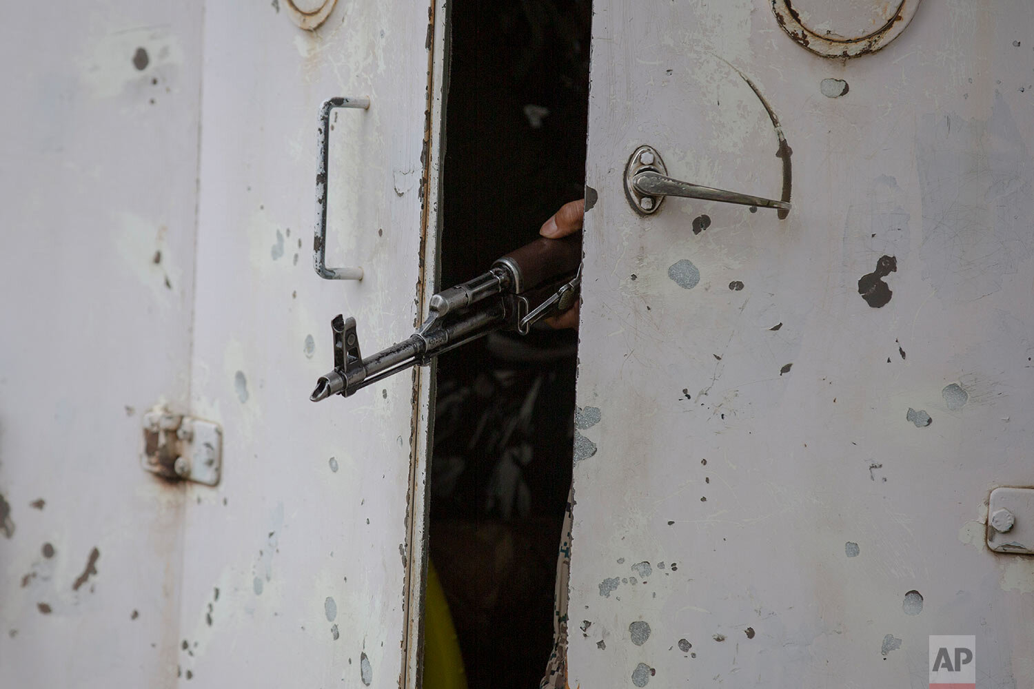  A barrel of a gun belonging to an Indian paramilitary soldier is seen between partially closed doors of an armored vehicle as they drive towards the site of an operation in Awantipora area, south of Srinagar, Indian controlled Kashmir, Wednesday, Ma