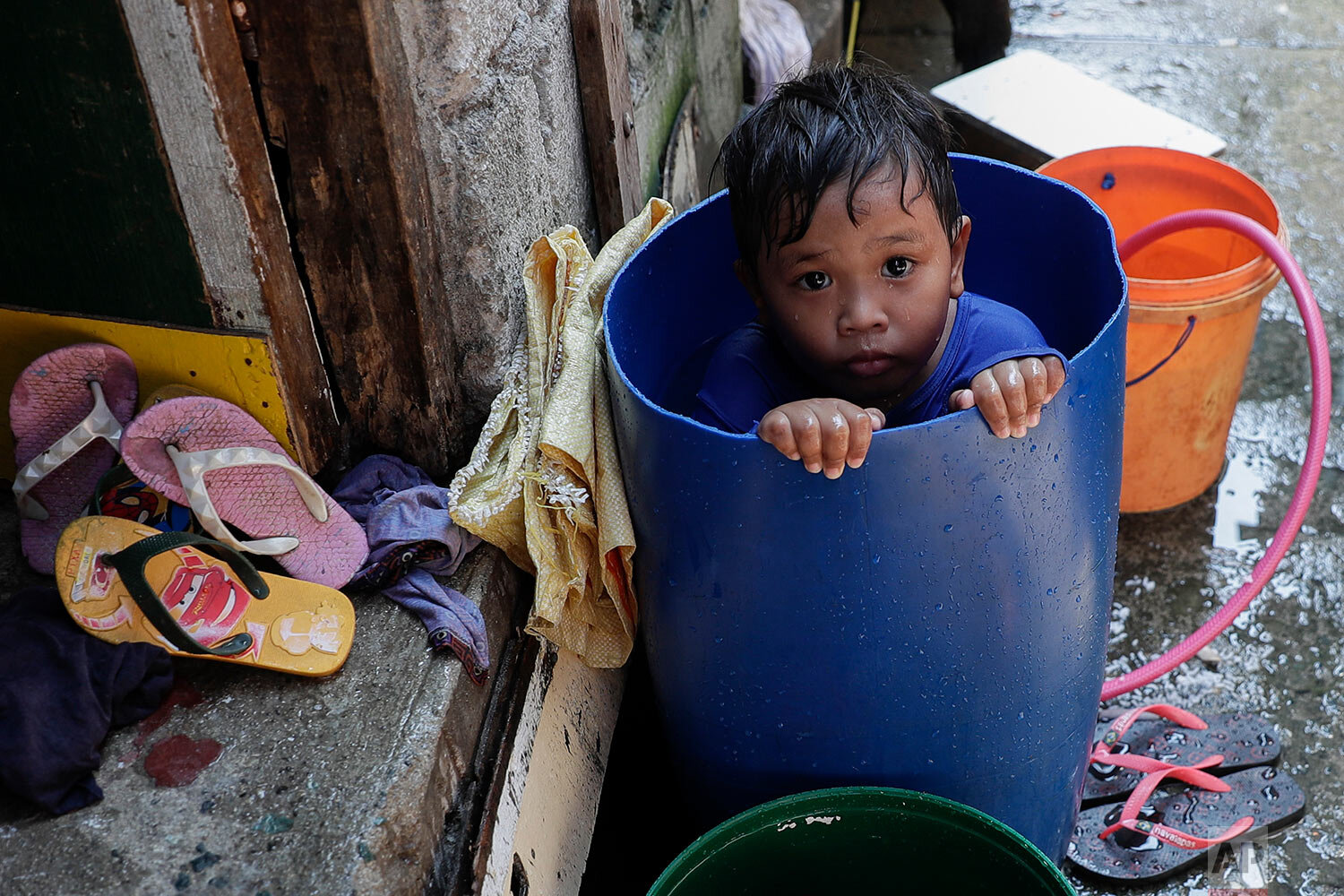  A boy takes a bath inside a plastic container at a coastal village in Cavite province, south of Manila, Philippines, during a continuing enhanced community quarantine to prevent the spread of the new coronavirus, Thursday, May 7, 2020. (AP Photo/Aar