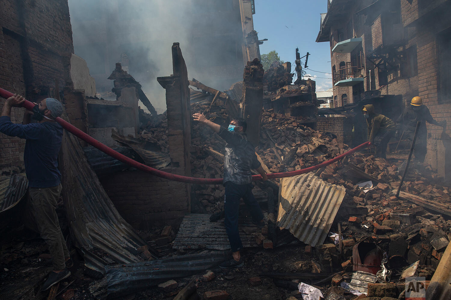  Kashmiri men and firefighters douse a fire in a house which was destroyed in a gunbattle in Srinagar, Indian controlled Kashmir, Tuesday, May 19, 2020. (AP Photo/ Dar Yasin) 