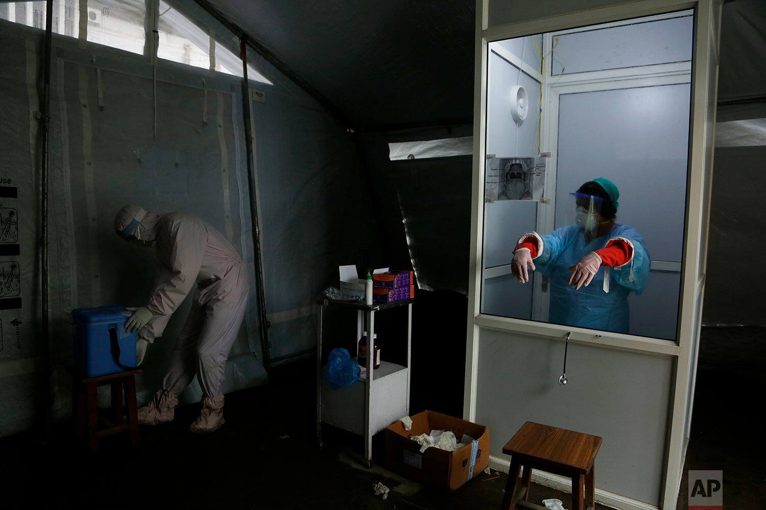  Nhuja Kaiju, left, of the RNA-16 volunteer group wearing a protective suit, helps a nurse collect swab samples of patients at a hospital in Bhaktapur, Nepal, Tuesday, May 26, 2020.  (AP Photo/Niranjan Shrestha) 