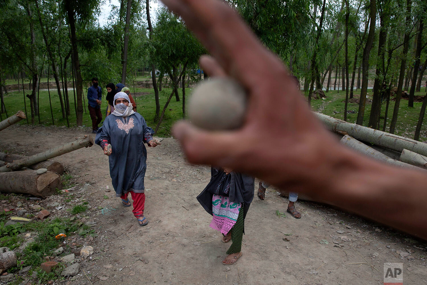  A Kashmiri village woman collects stones to hand to the men to throw at security personnel during a protest against the killing of a civilian in Makhama village, west of Srinagar, Indian controlled Kashmir, Wednesday, May 13, 2020.  (AP Photo/ Dar Y
