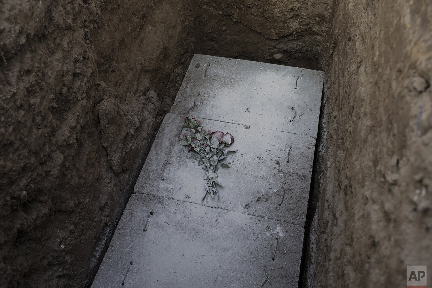  In this May 8, 2020 photo, flowers covered with cement and lime pose on the grave of TV camera man Mario Bucana, who died due to COVID-19 in Lima, Peru. (AP Photo/Rodrigo Abd) 
